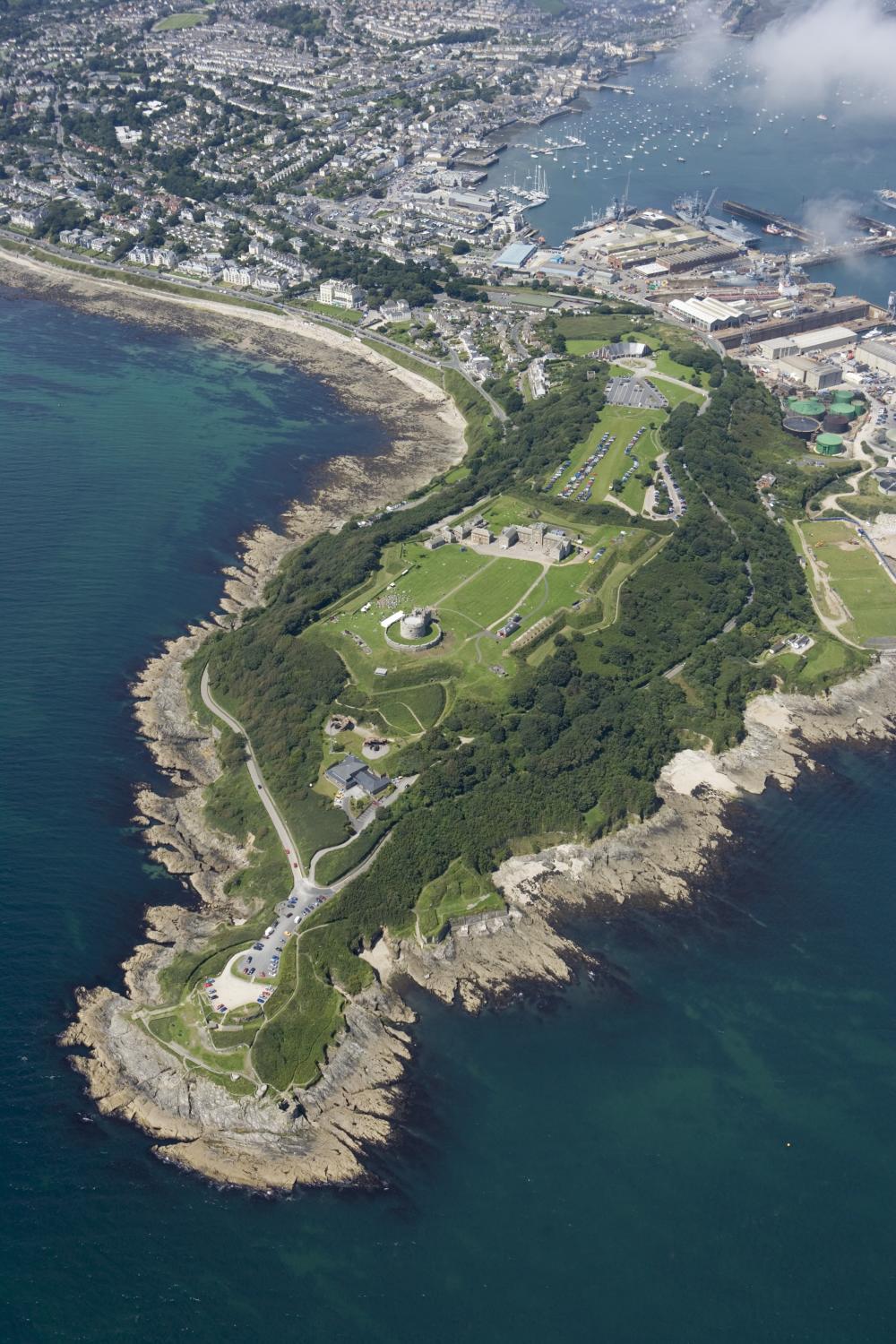 An aerial photograph of a rocky headland with a large complex of historic buildings at its centre.
