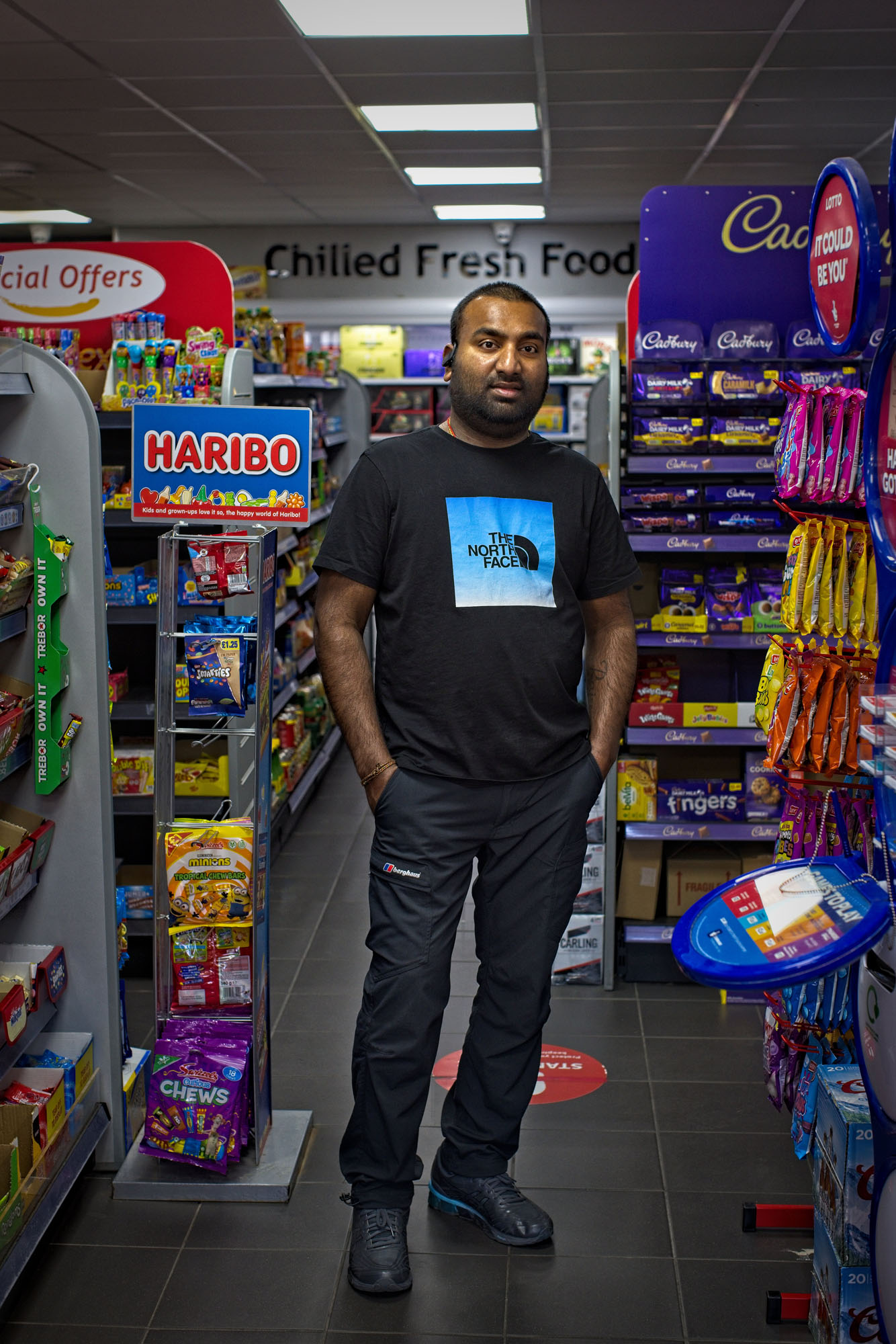 Portrait of the shop owner standing between two aisles of sweets at Today's Express, 14 Eccleston Street