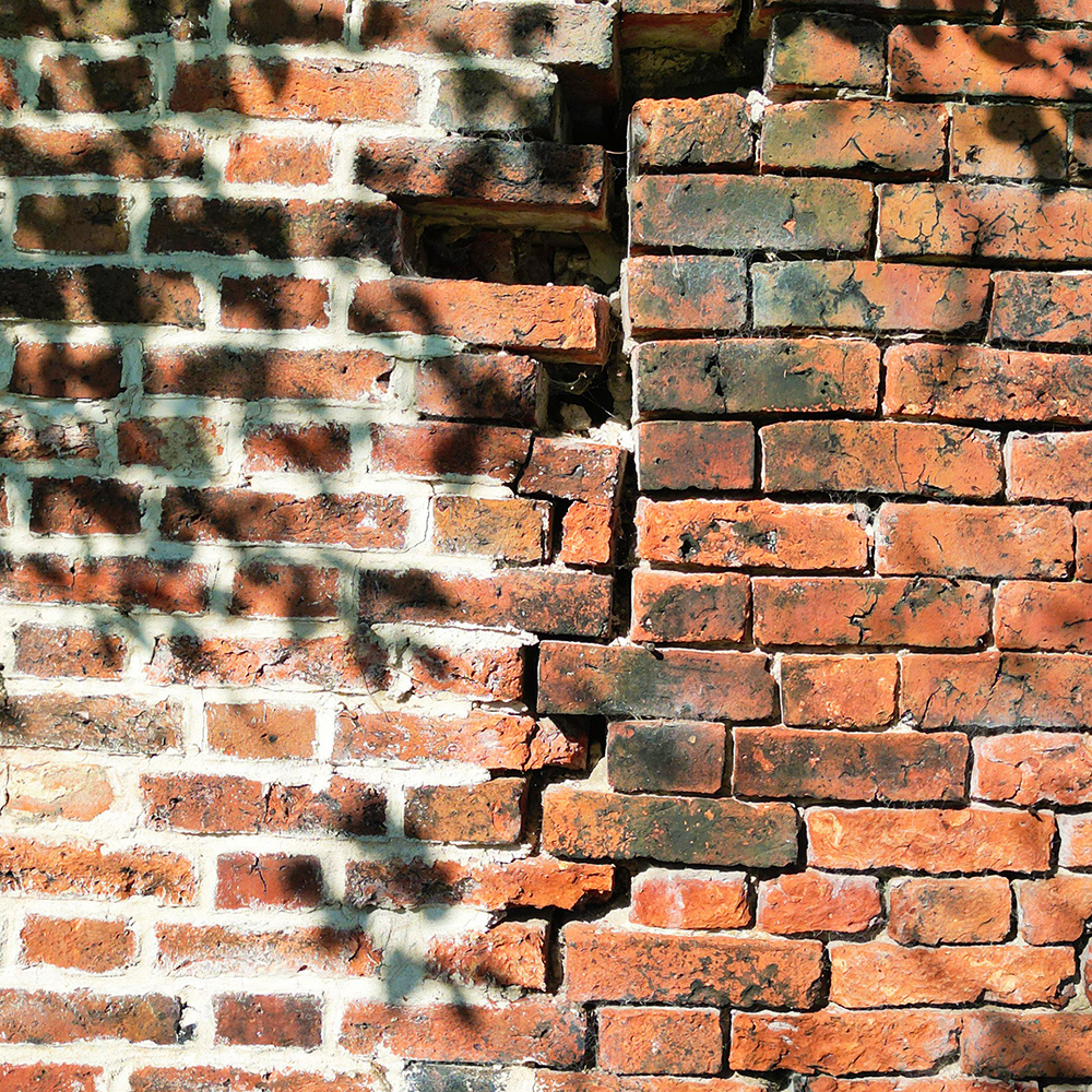 A red brick wall with missing bricks in need of repointing. 
