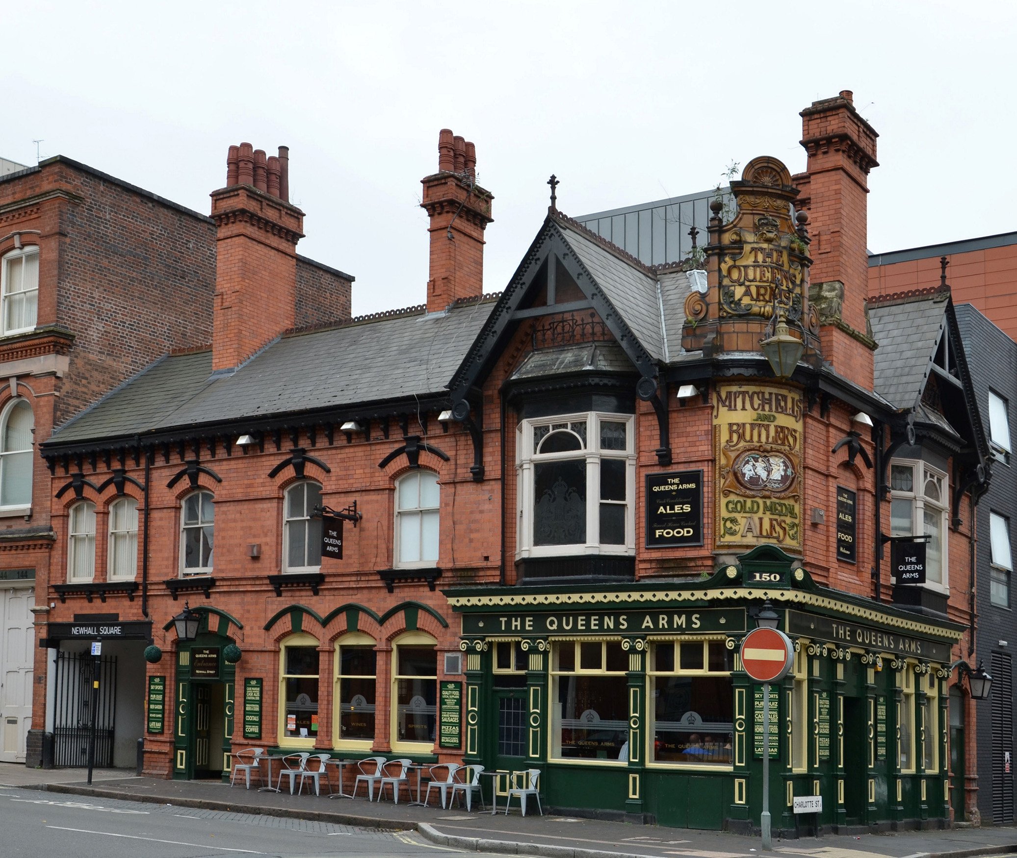 A photo from street level of a pub in Birmingham with green frontage and bay windows on the ground floor