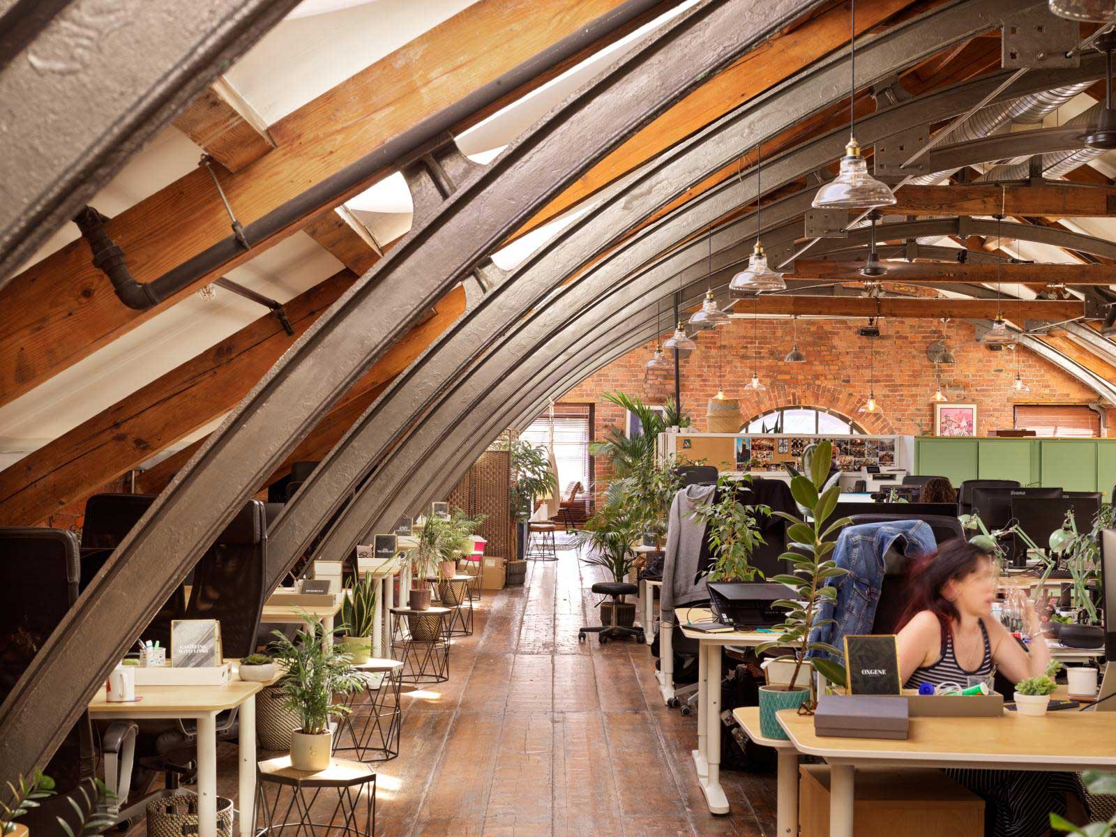 A view of an office within a historic mill building featuring arches of exposed girders.