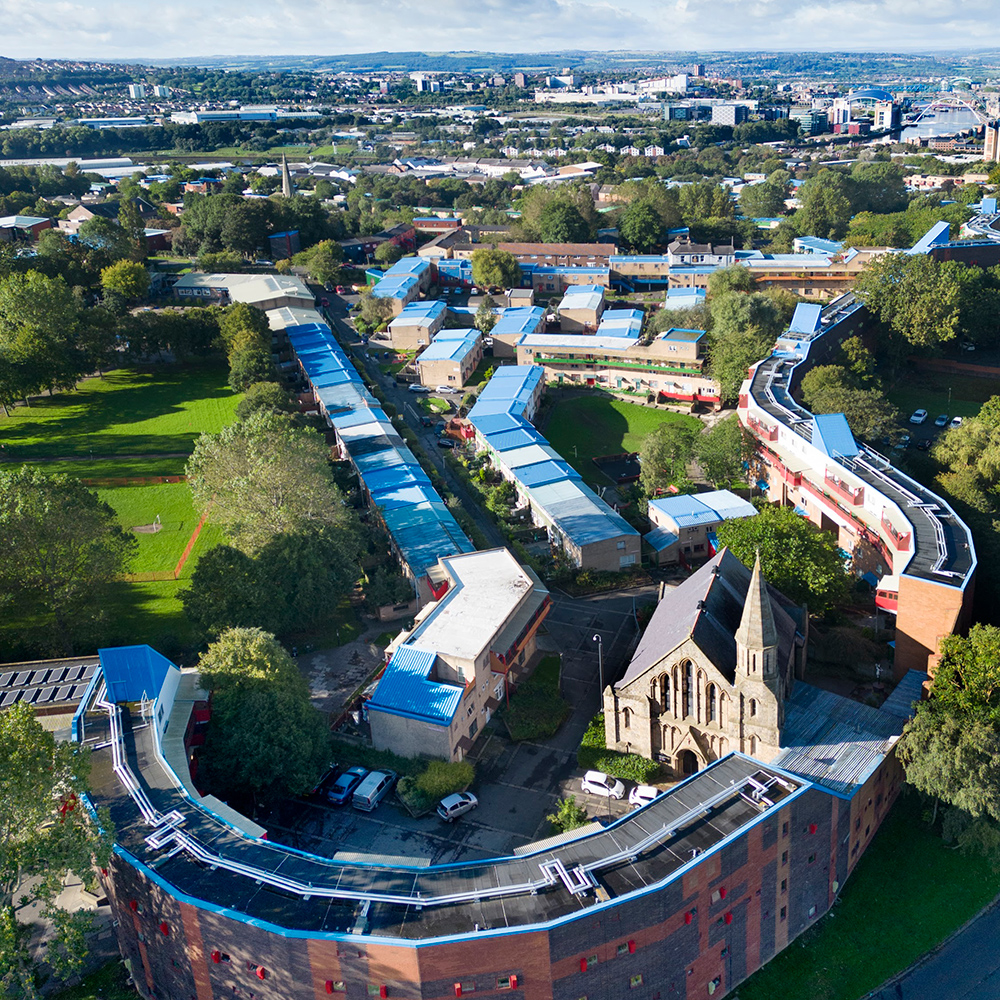 Exterior, drone image from east showing church, snaking estate buildings, Newcastle city centre and Gateshead Millenium Bridge with River Tyne.