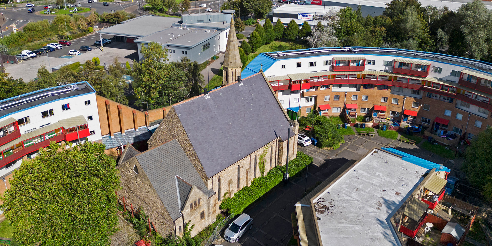 Exterior, drone image from west showing church, snaking estate buildings.