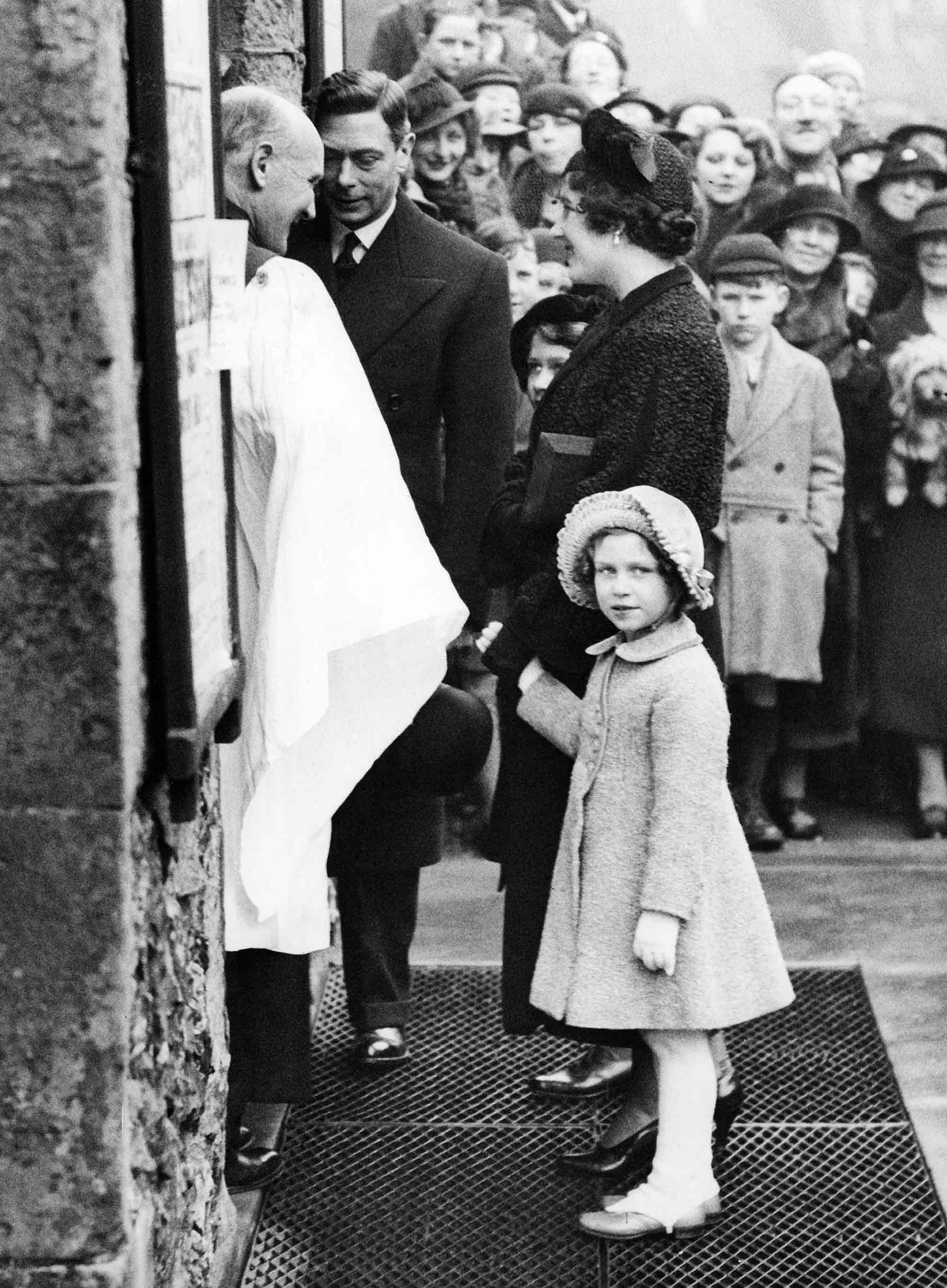 Princesses Elizabeth and Margaret with their mother Elizabeth Bowes-Lyon and father George VI being greeted by Reverend F.P. Hughes in front of St. Mary's Church in Eastbourne in 1936 © Sueddeutsche Zeitung Photo / Alamy Stock Photo