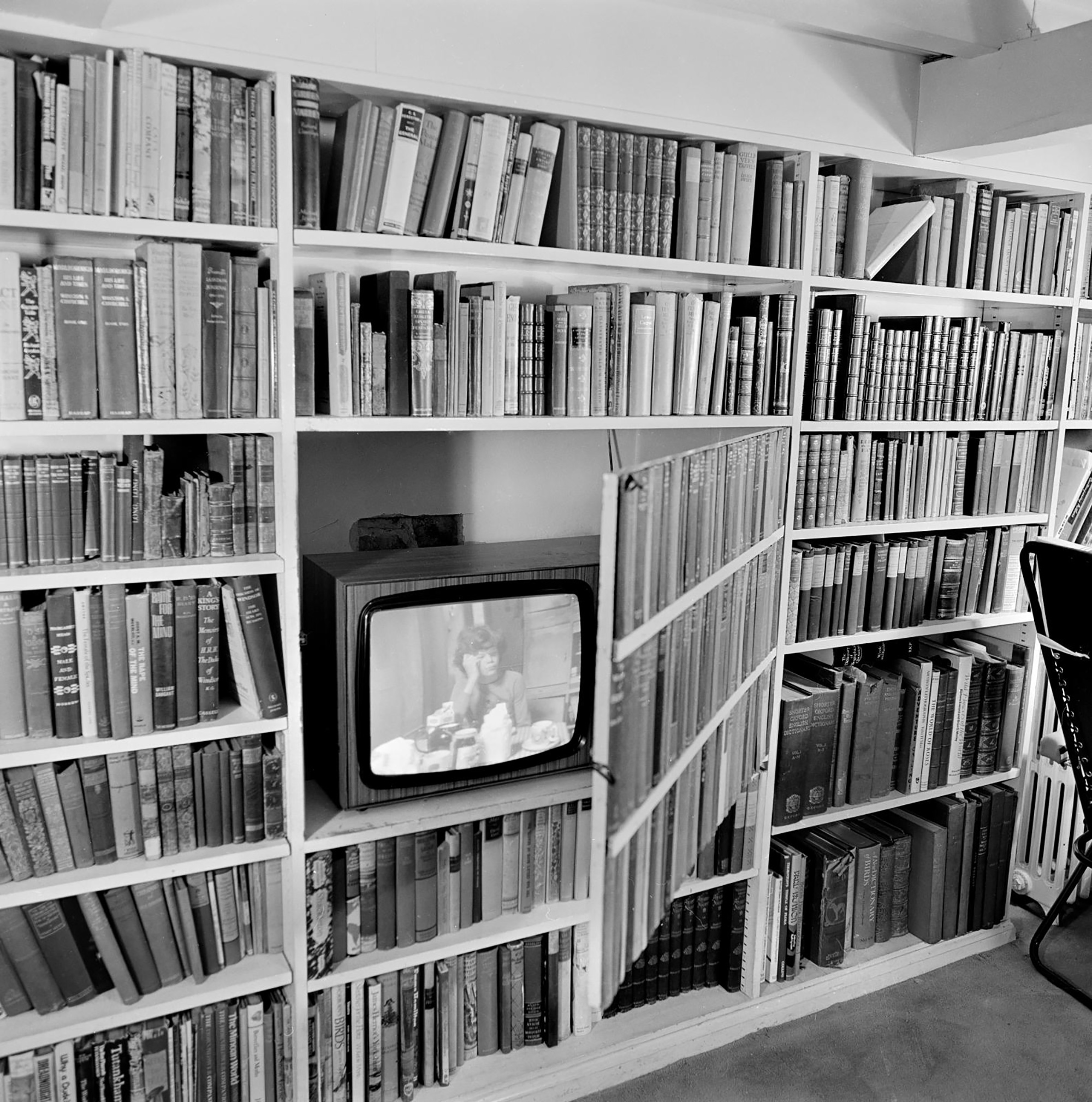 Black and white photo of a television in a bookcase