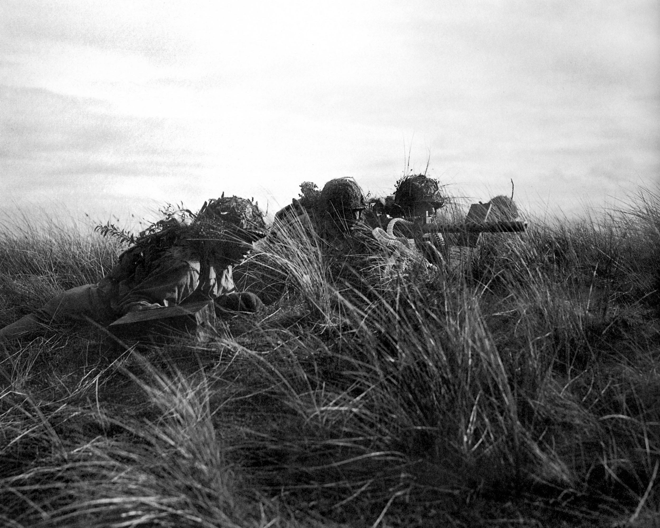 Three soldiers crouched in the sand