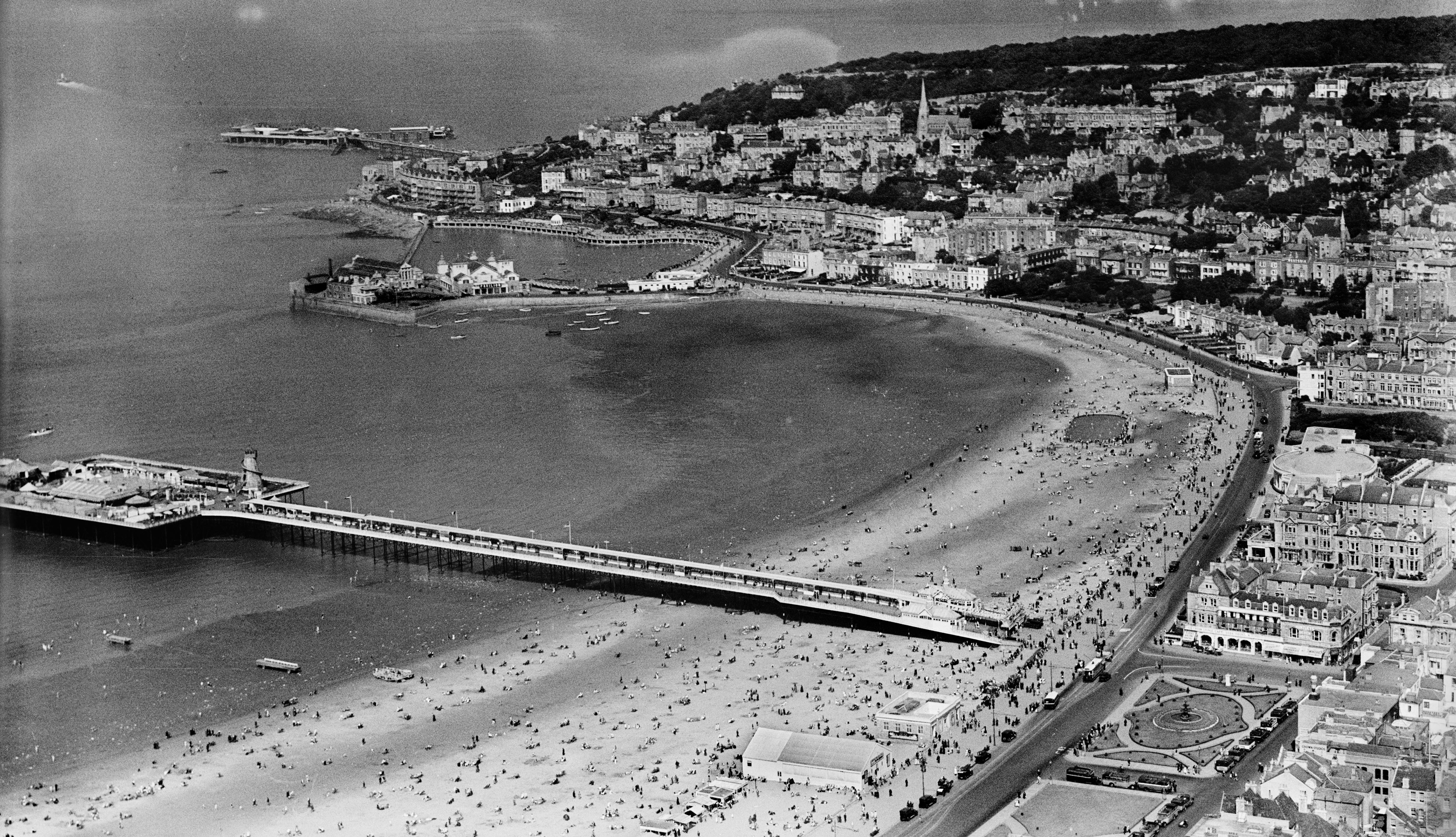 An aerial view of a beach, pier and seafront amusements.