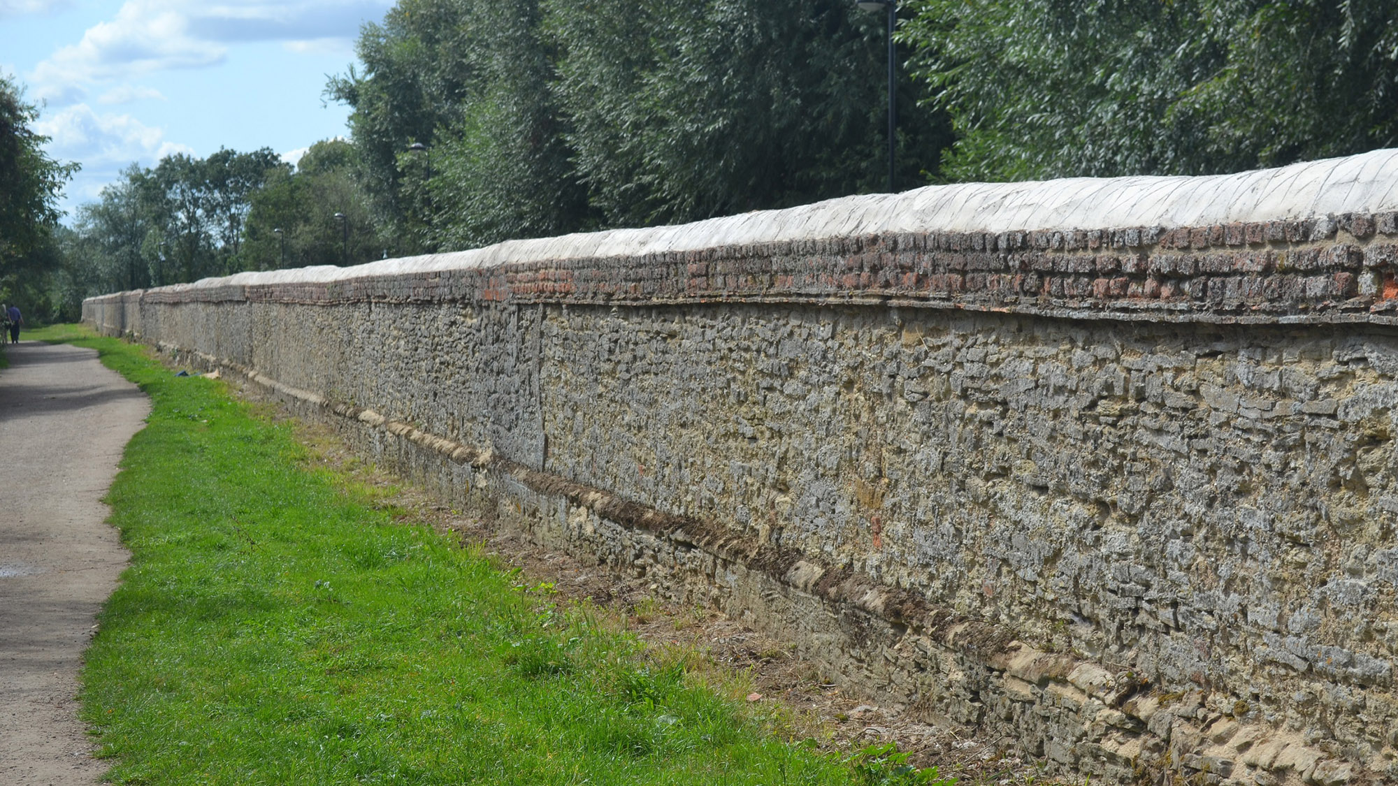 View along a wall next to a path with a grass verge
