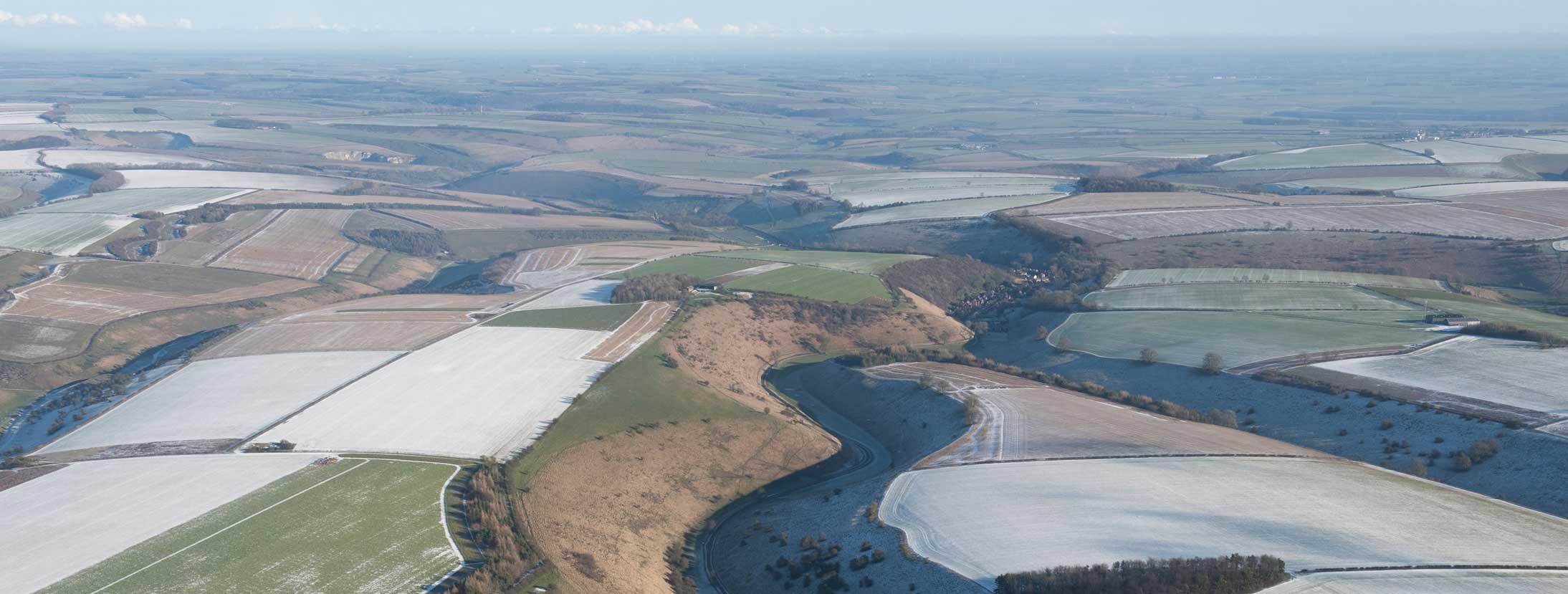 Aerial view of landscape with some fields covered in snow.