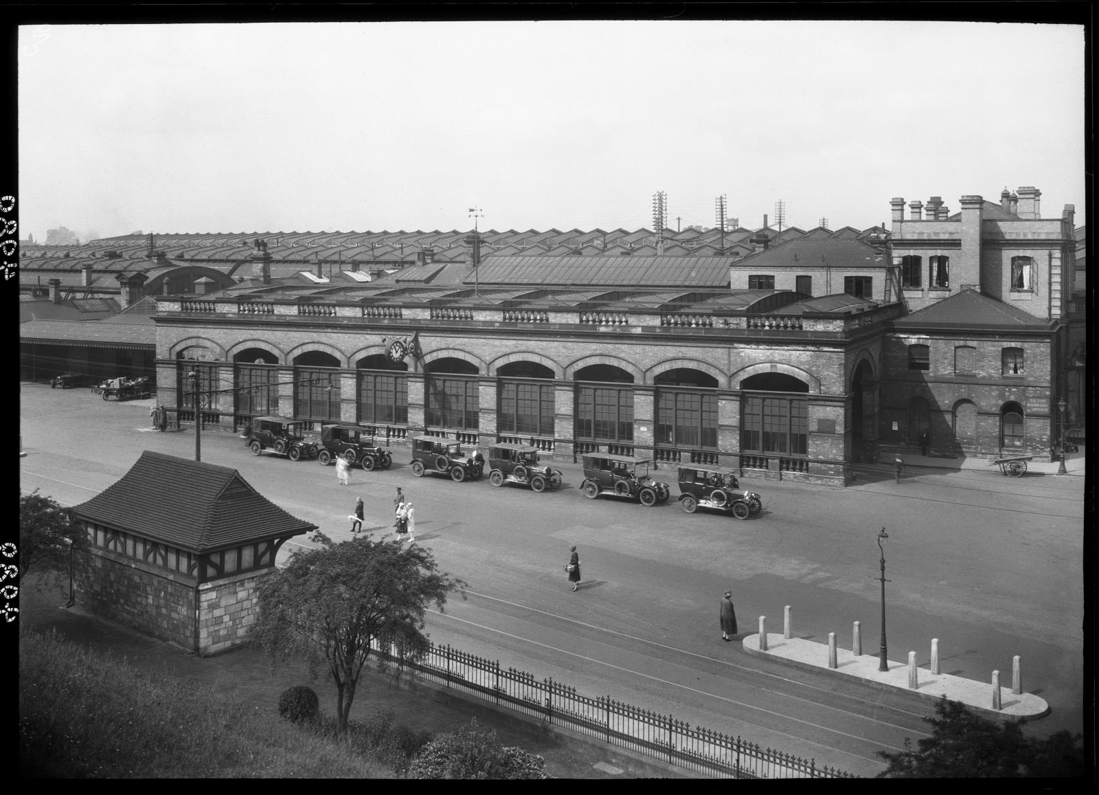 A view showing York Railway Station from an elevated position to the south-east, with a line of cars, probably taxis, parked along the road in front