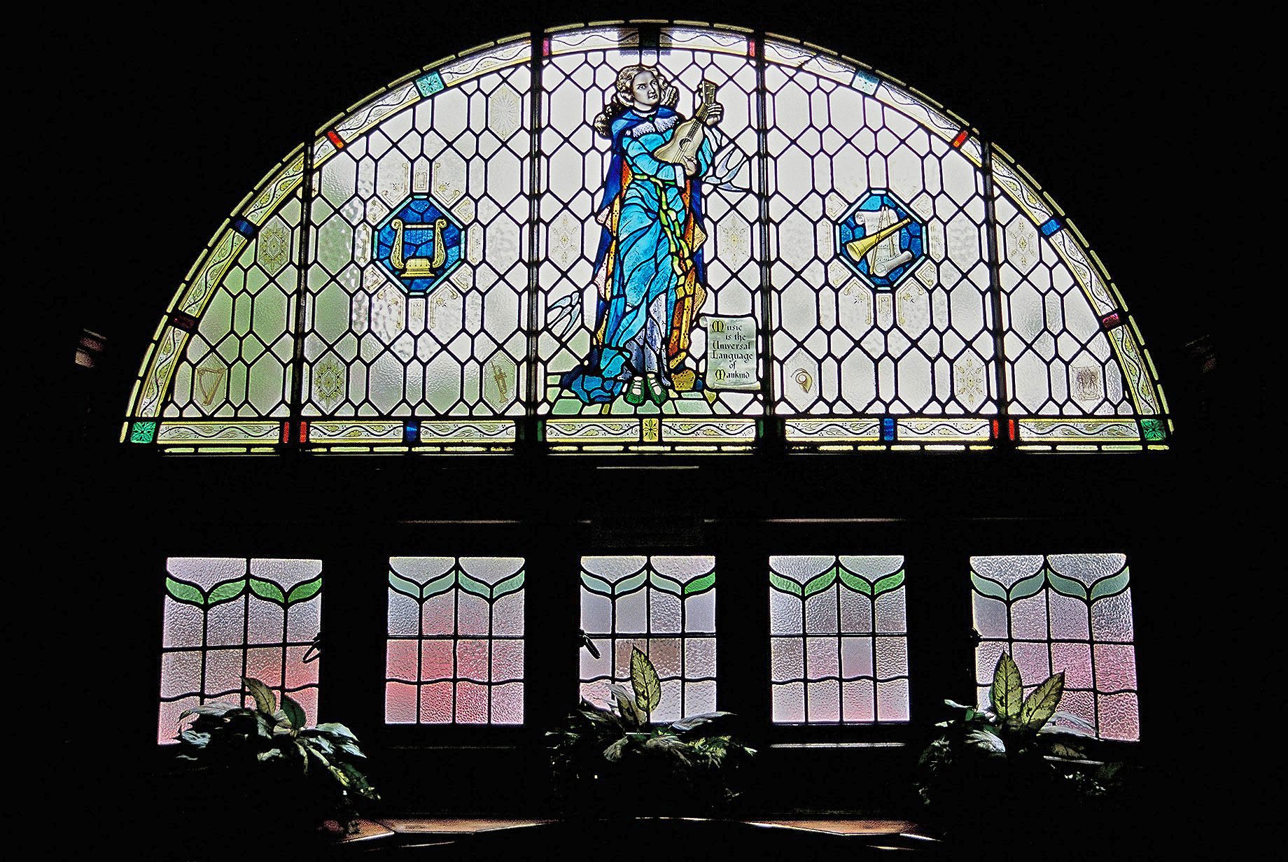 A stained glass window from a public house depicting Saint Cecilia playing a lute-like instrument.
