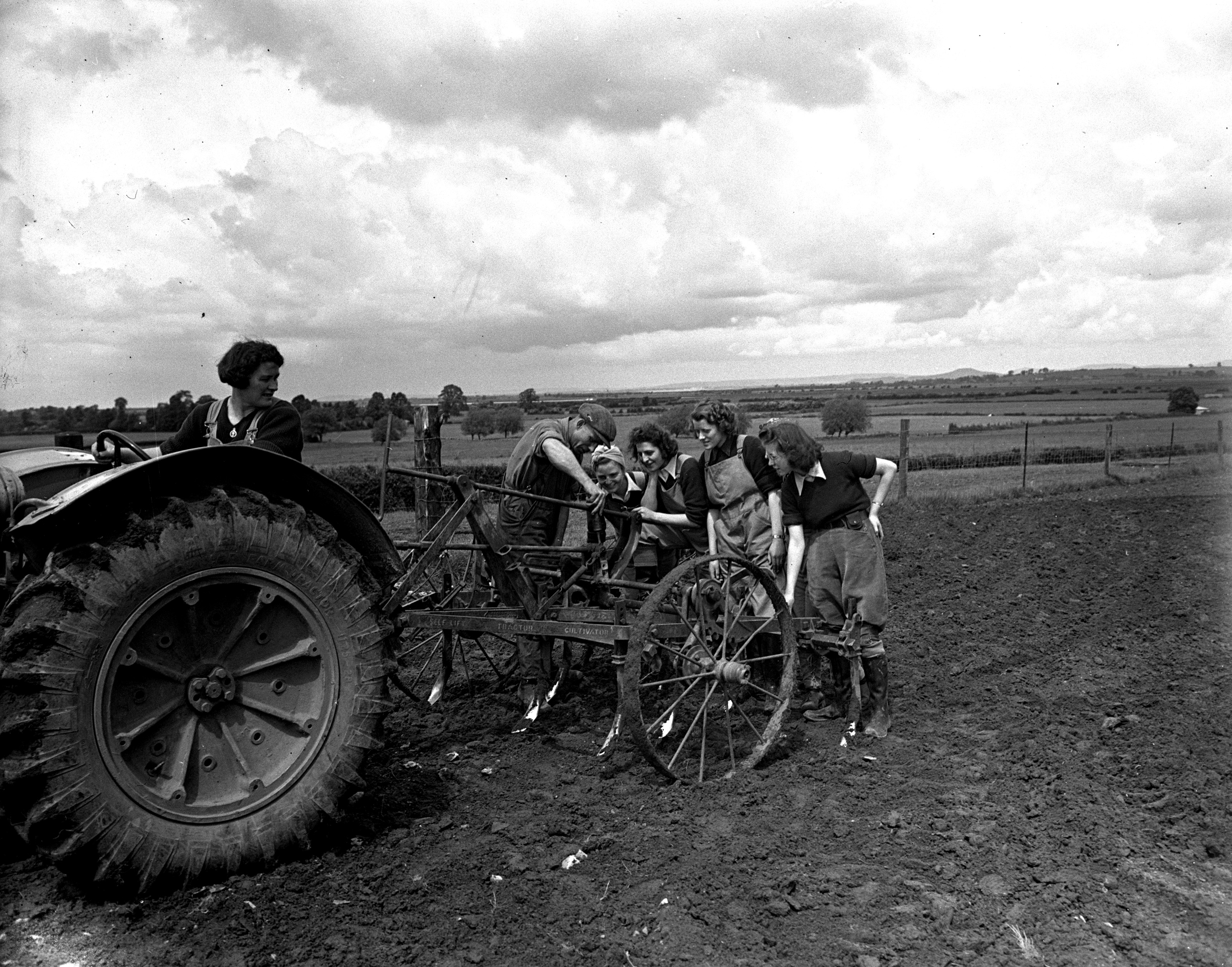 Plough attached to a tractor being demonstrated to land girls