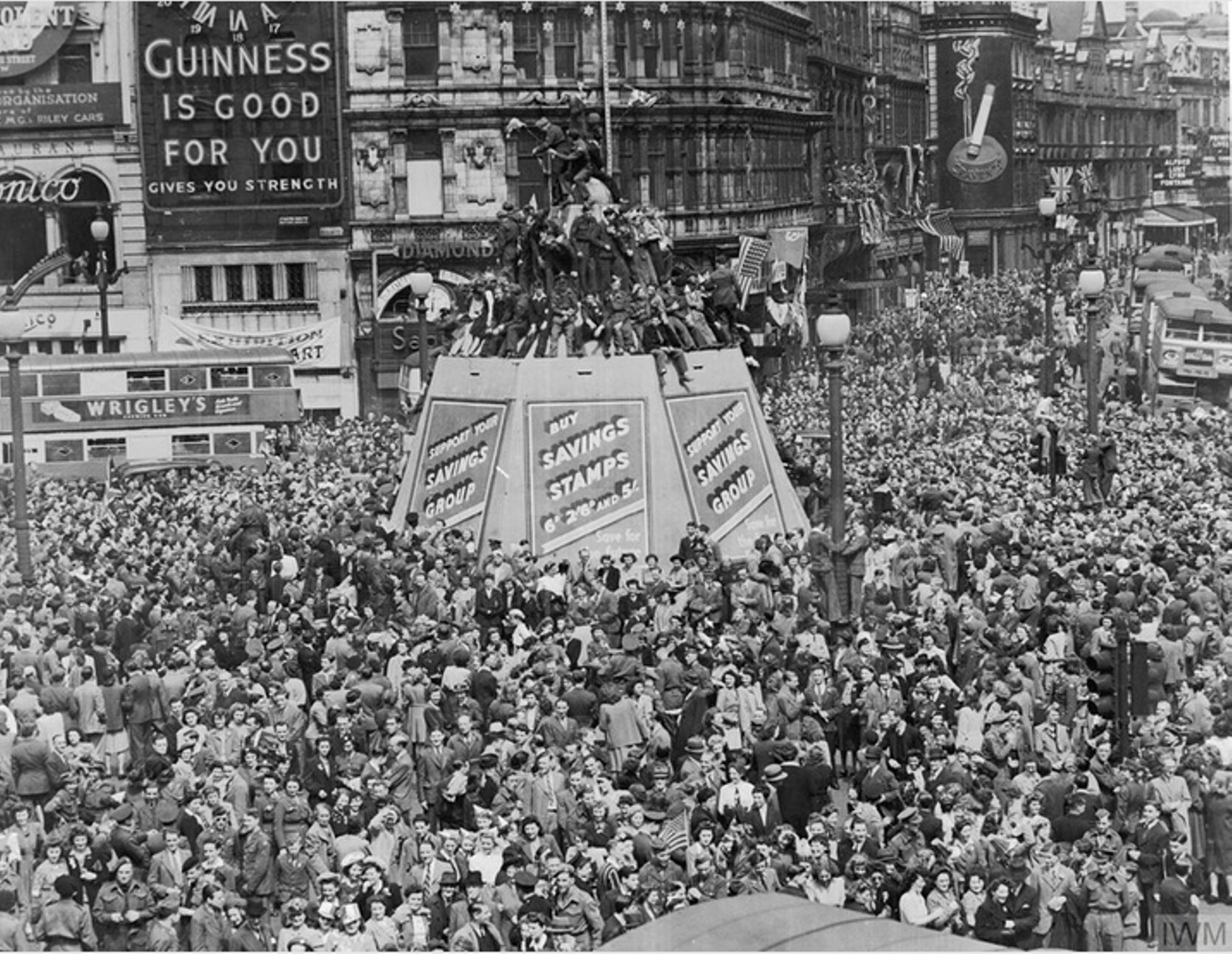 Crowds of service people and civilians at Piccadilly Circus, with the Shaftesbury memorial in the centre.