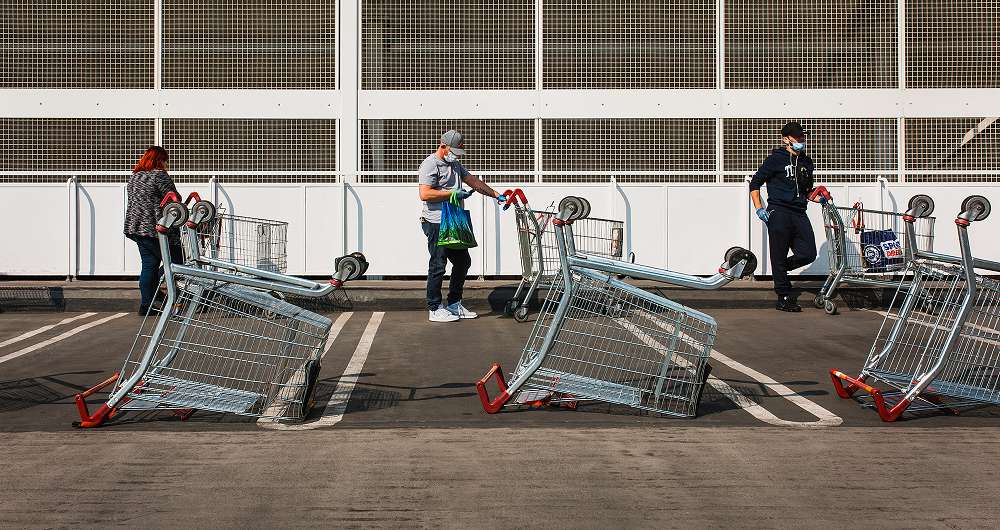Three people standing 2 metres apart with supermarket trollies