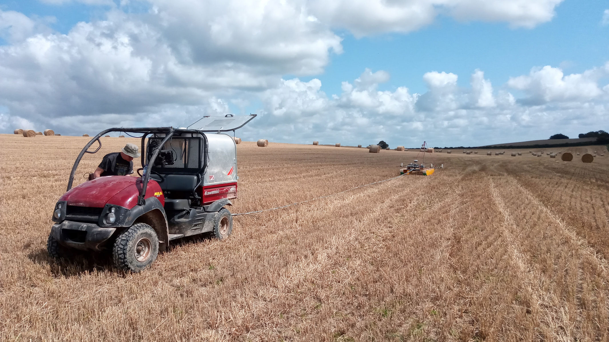 Geophysics equipment being towed across a field by a small vehicle.