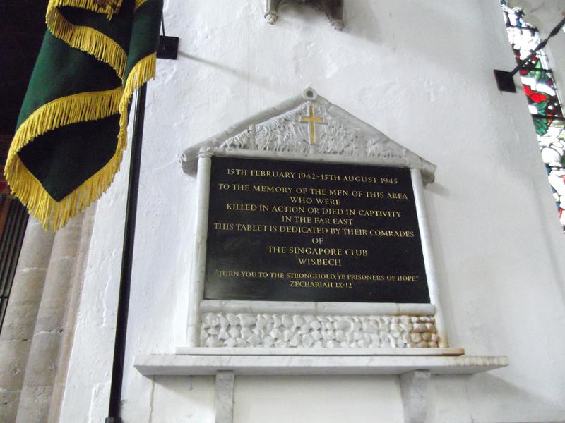 A black marble plaque embossed with gold writing surrounded by a sculpted frame depicting a bamboo and coconut leaf hut.