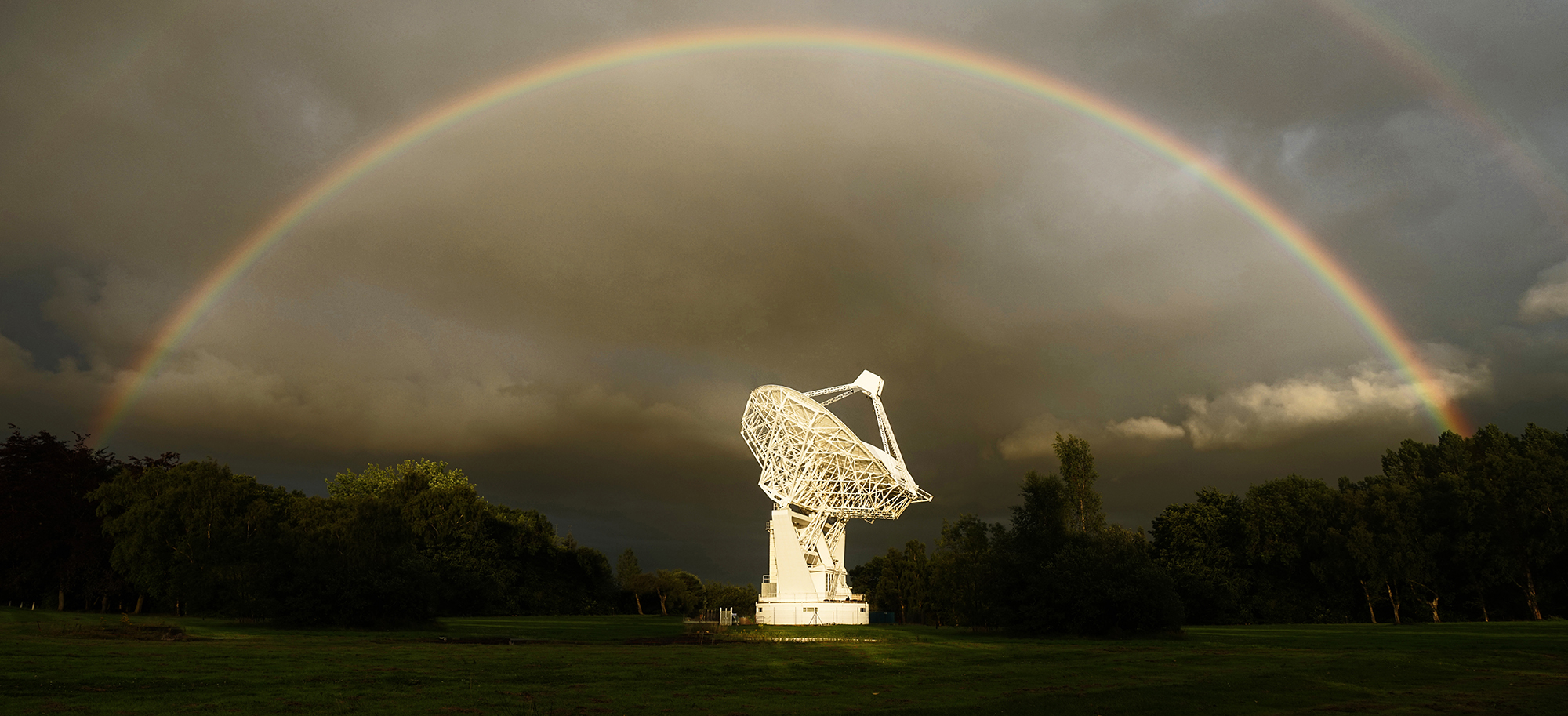 The Mark II Telescope at Jodrell Bank photographed against a moody sky encircled by a rainbow