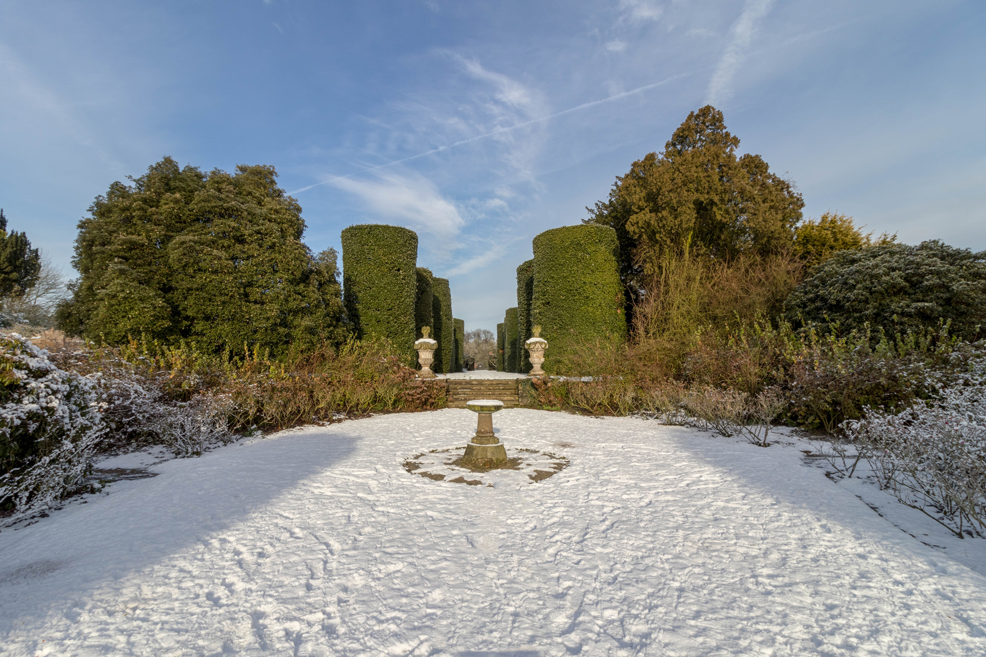 Snow-covered garden with stone fountain in the centre of the lawn