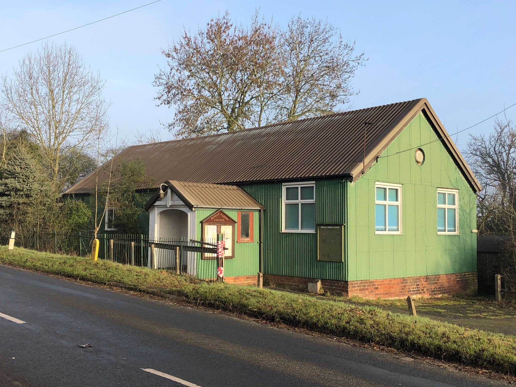 A single-storey prefabricated village hall with a porch and gabled roof.