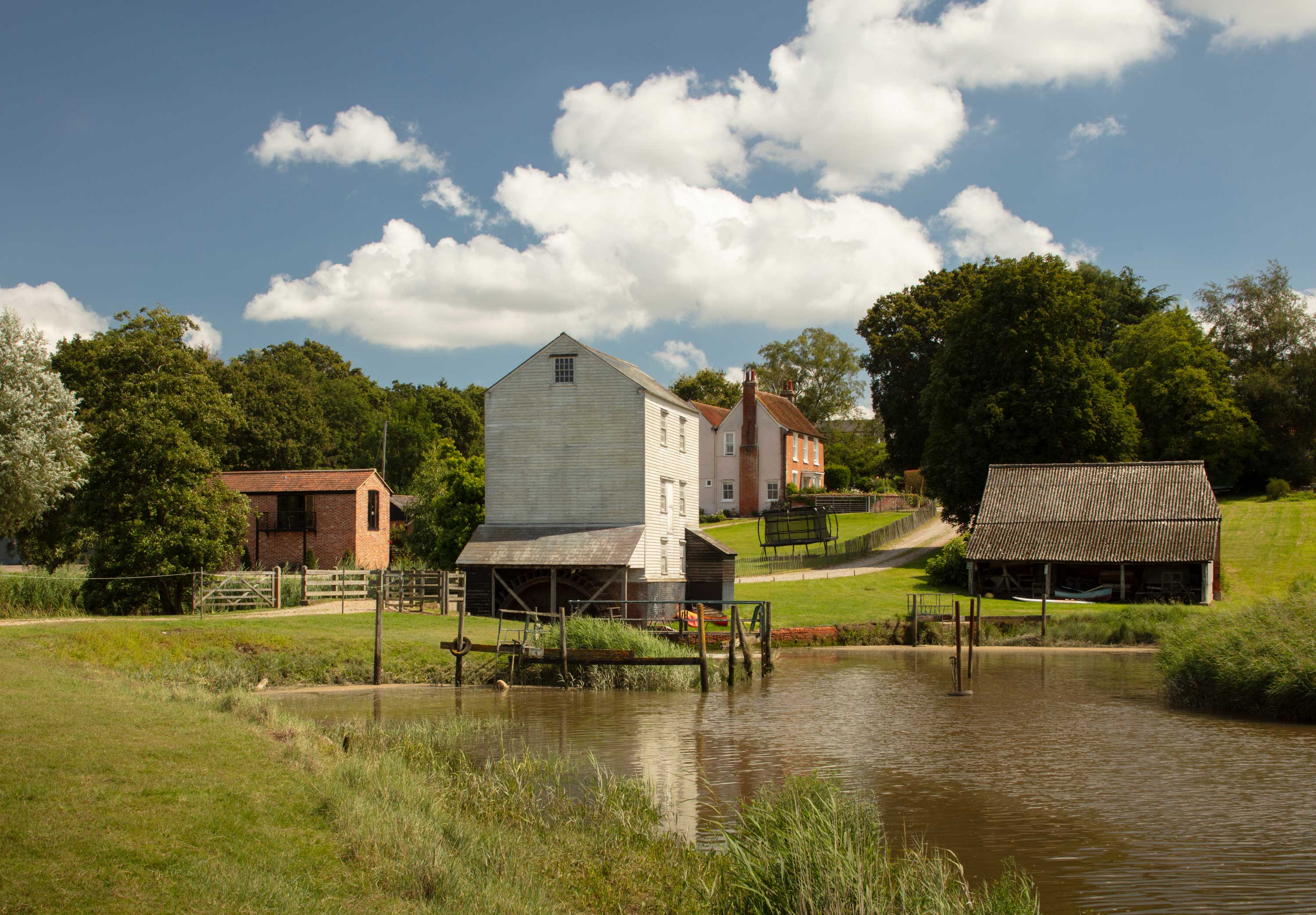 Mill buildings set on a hill with a lake in the foreground