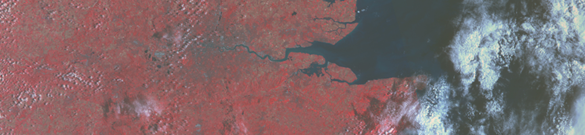 High level satellite image showing the south-east of England in various shades of red with banks of white cloud to right
