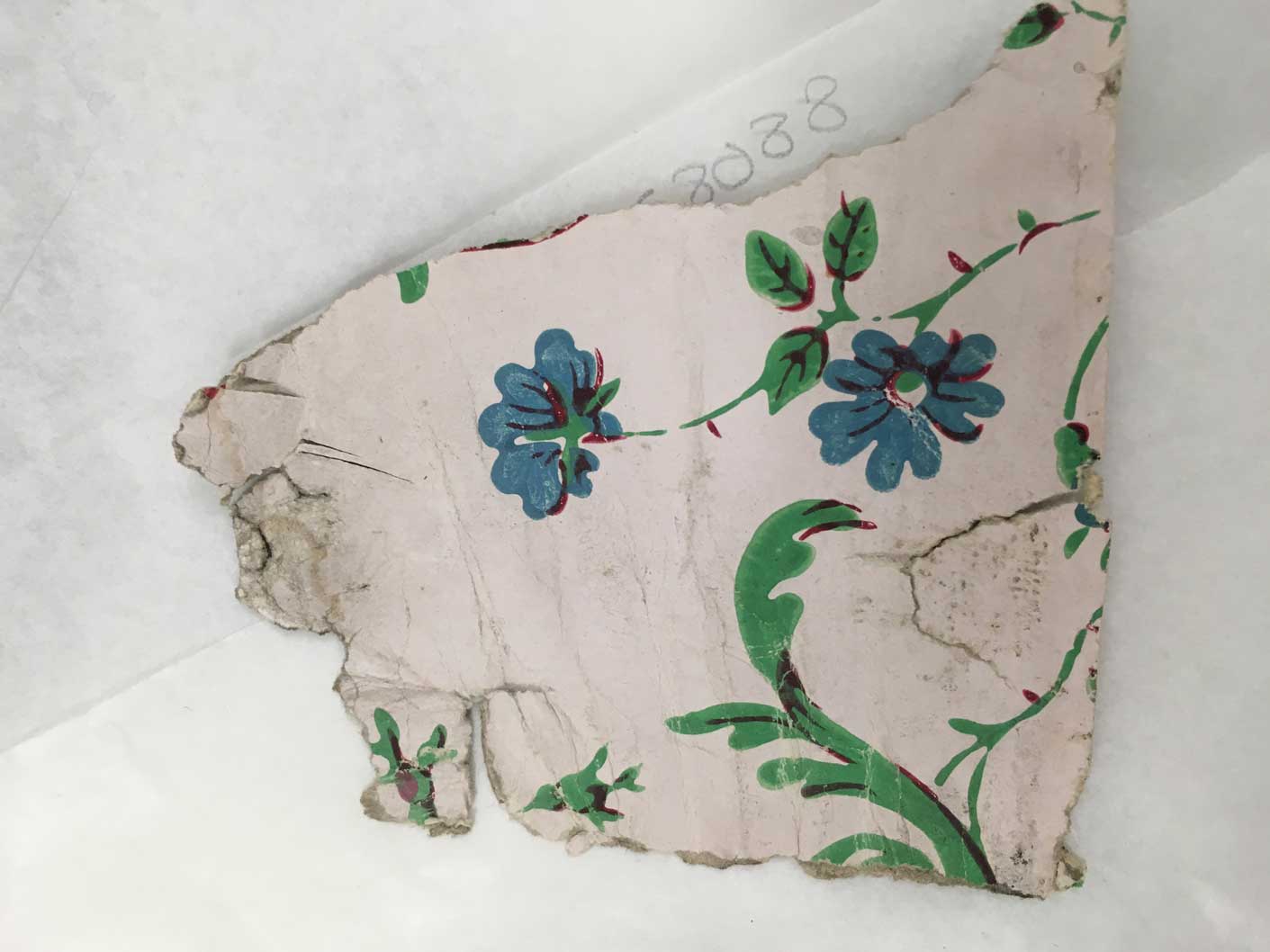 A historic wallpaper fragment of blue flowers with green foliage, the green pigment contains arsenic.