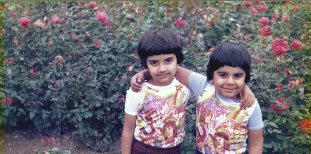Anand and Anmol Chhabra wearing Osmonds T-Shirts and matching trousers and hair. Photographed in a park next to the flowers on display there August 1978.