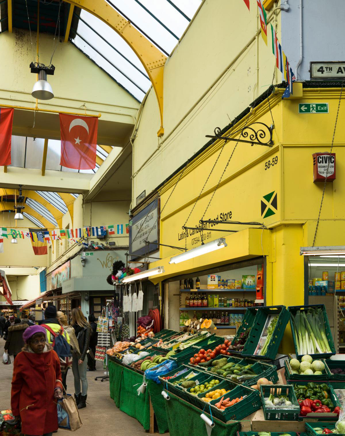 Granville Arcade, now Brixton Village, 2016 with shoppers and the vegetable display of a Caribbean food store in the foreground.