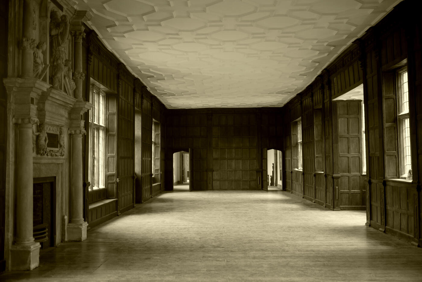 Interior of panelled, unfurnished room with large marble mantelpiece at Apethorpe Palace.
