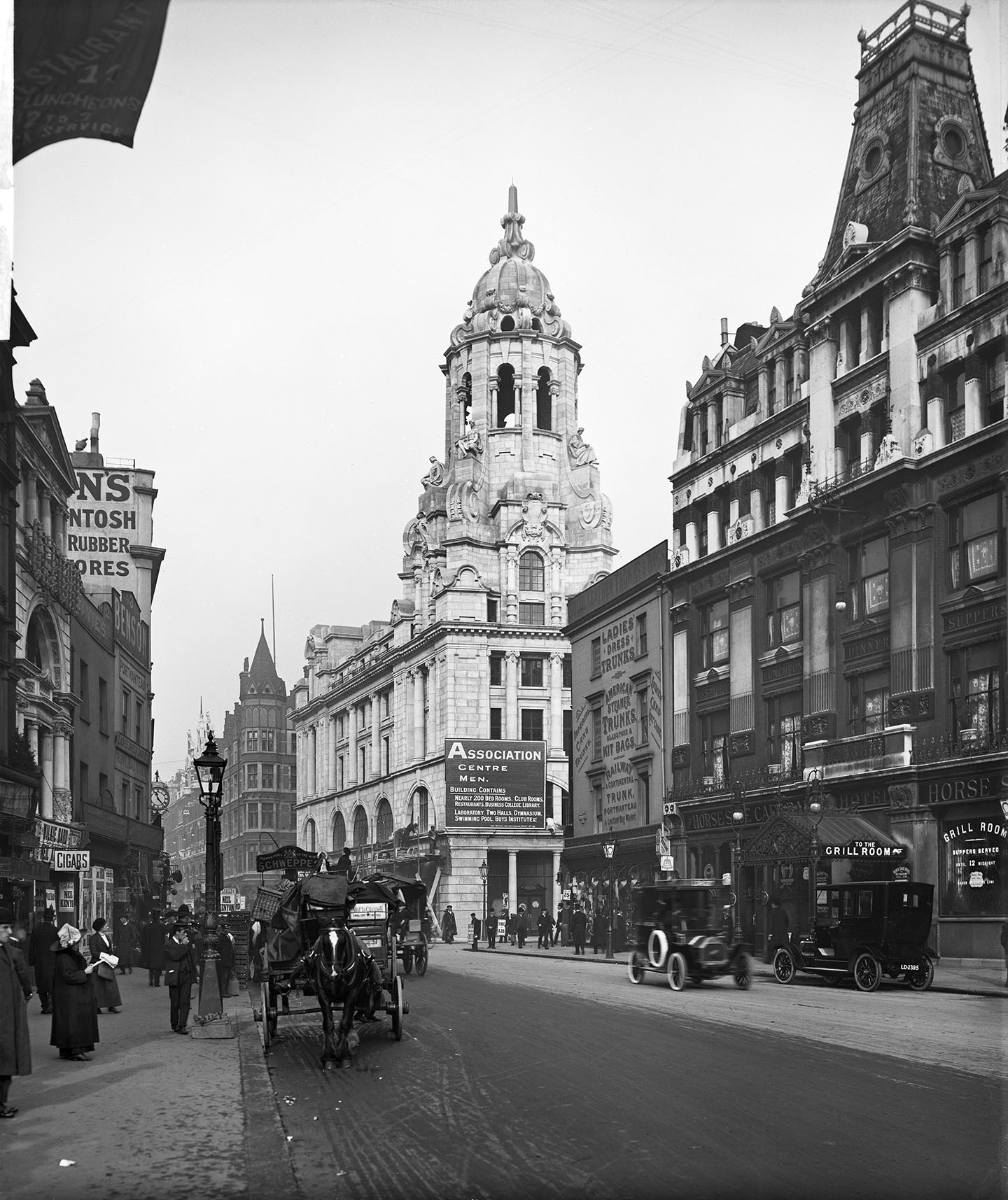Black and white photo of a street with horses pulling carriages