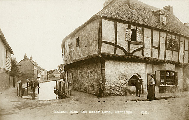 Exterior view from the north-east showing a man and woman with a boy outside the former Maison Dieu almshouse, Ospringe, Kent, with a horse and cart standing in the stream to the left circa 1900. The Maison Dieu is now a museum.