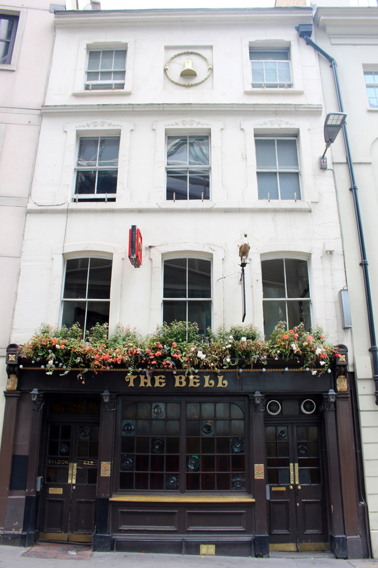 A photograph of a pub with a golden bell fixture at the top of the building. 