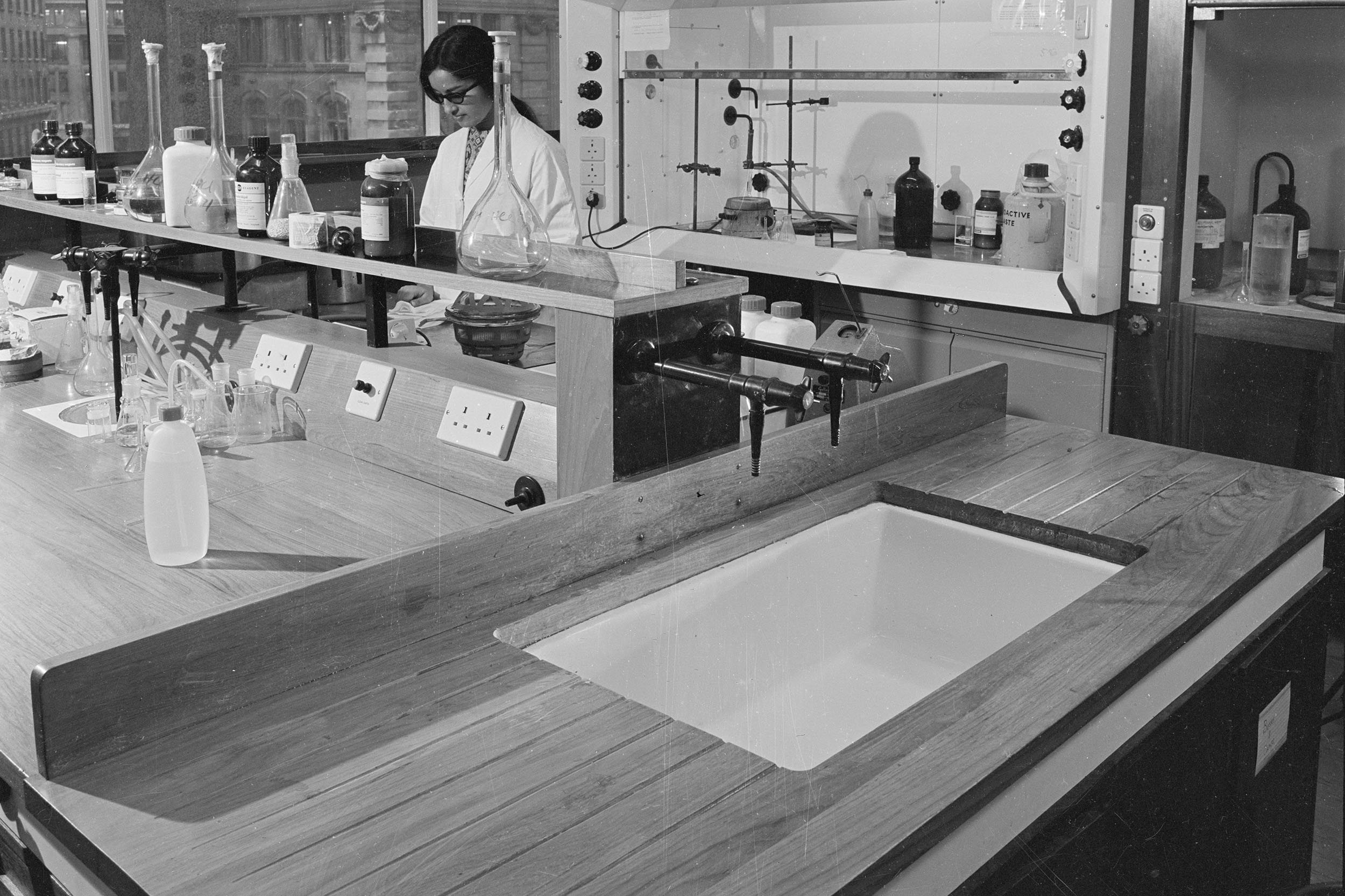 Black-and-white photograph of a female scientist at work in a laboratory at King's College London