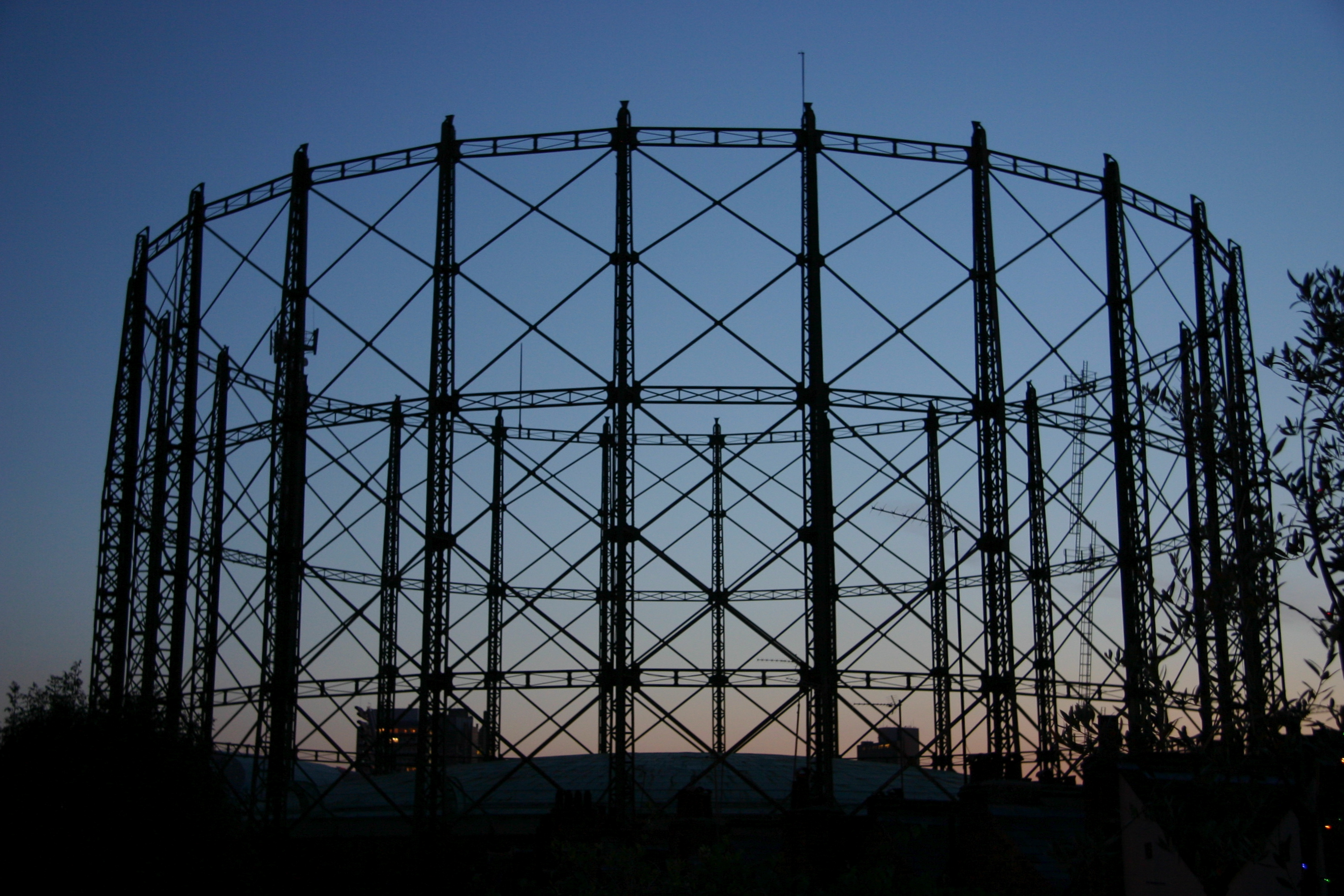 Gasholder at the Oval, London, in black silhouette against the sky at dusk.