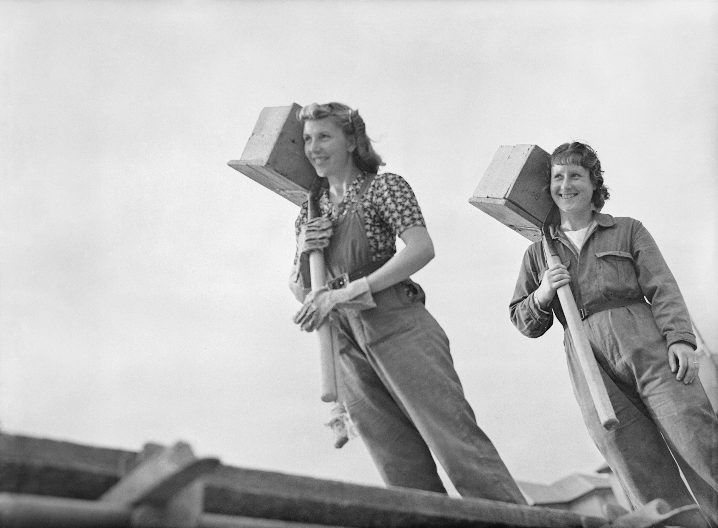 Black and white image of 2 women carrying bricks