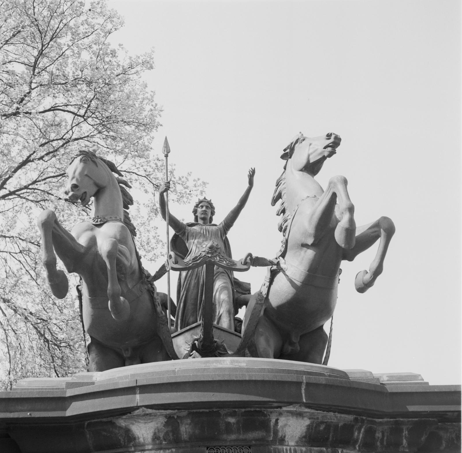 Statue of Queen Boudica in a chariot with arms outstretched as her horses rear.