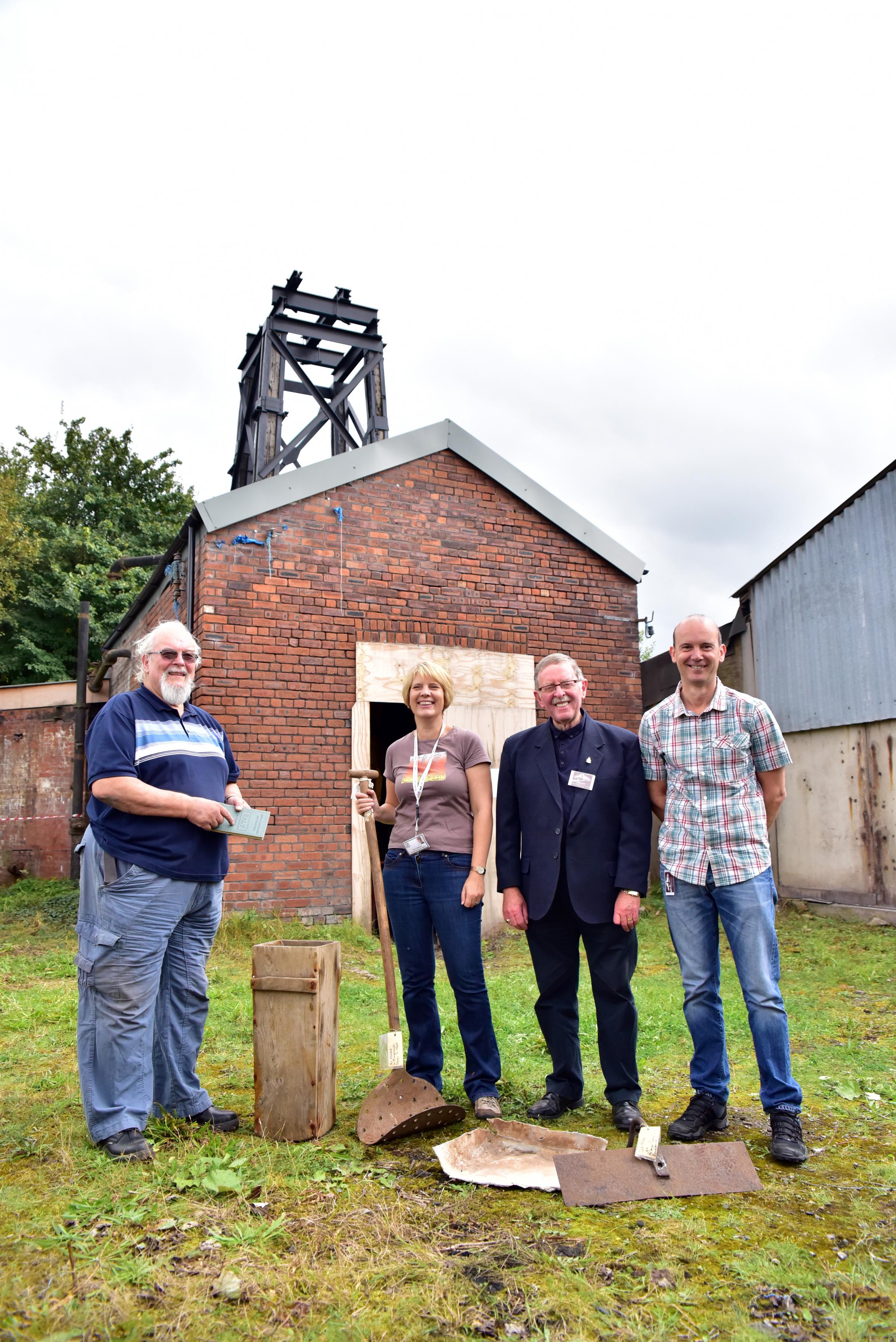 A group photo of four members of Middlewich Heritage Trust outside the brine pumps building at Murgatroyd's Brine Works.