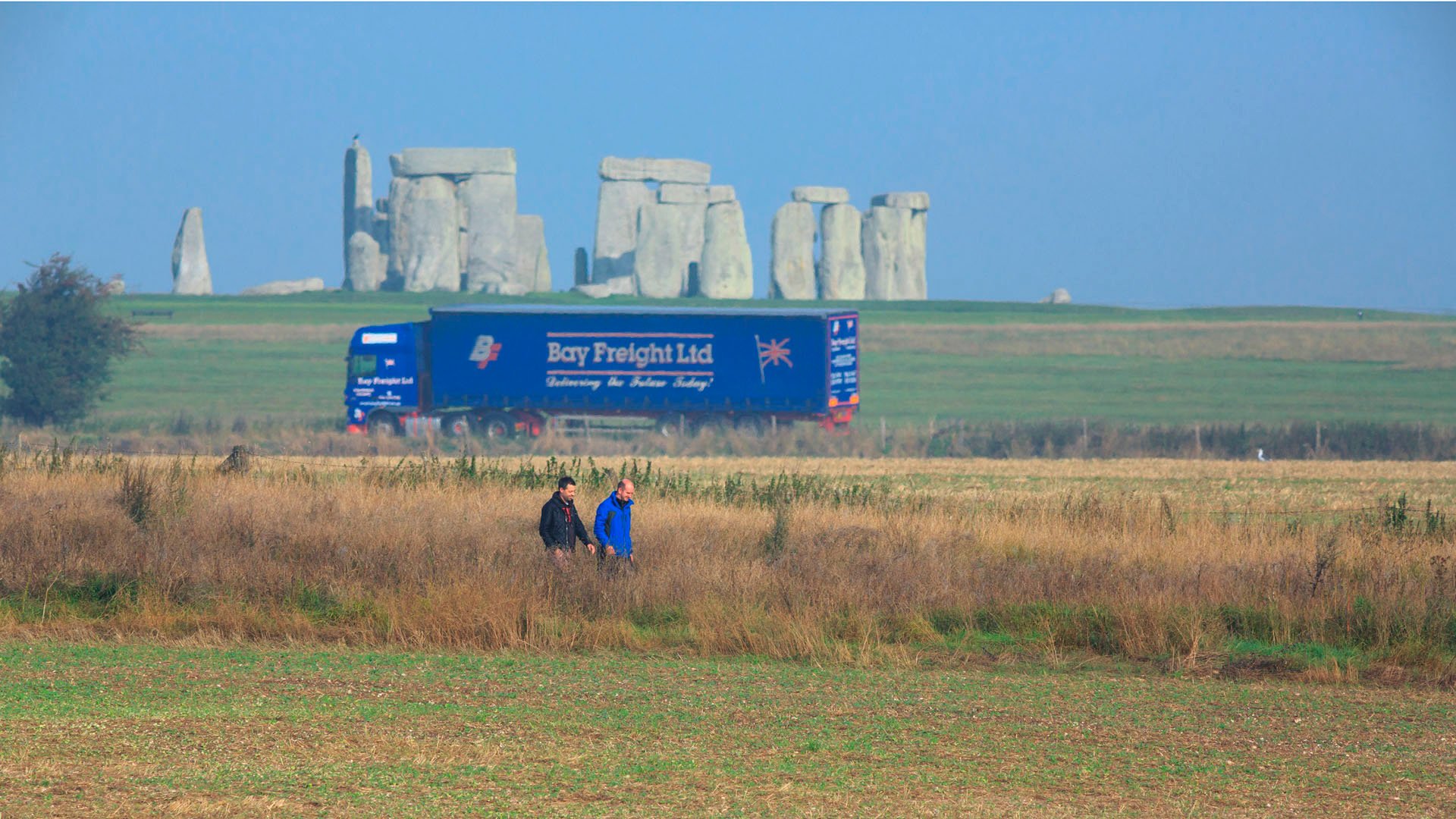 Visitors walking in Stonehenge Landscape with lorry in the background