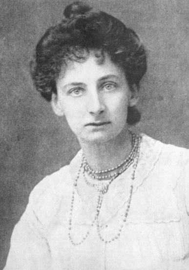 Black and white photo of a woman with hair up and wearing pearl necklace, taken in 1908.