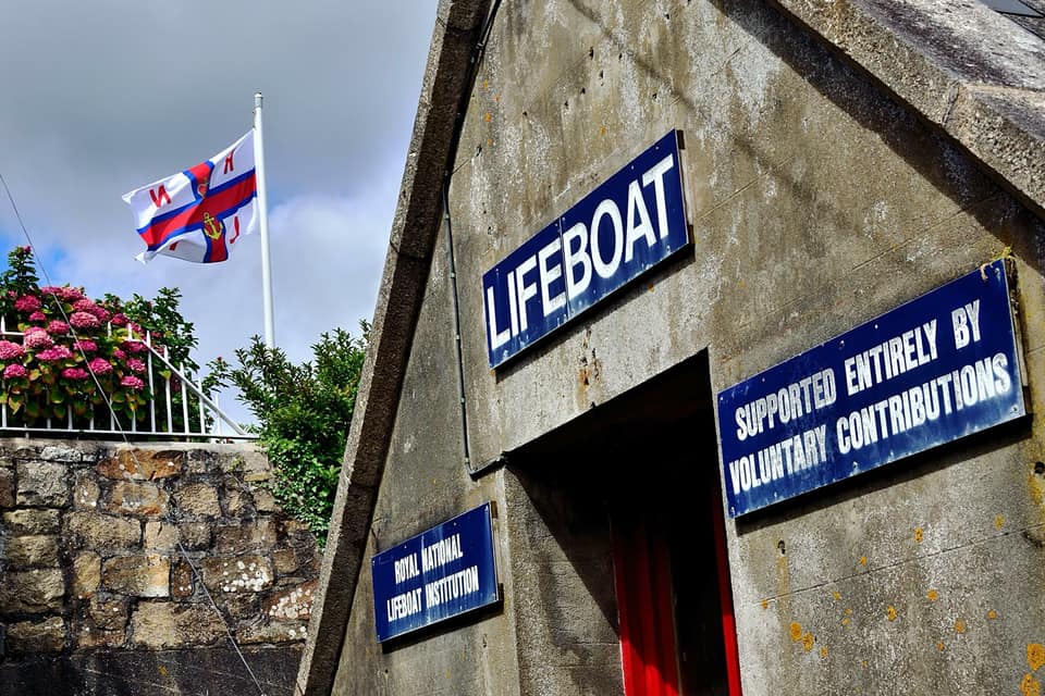 Penlee Point Lifeboat Station and the flag of the RNLI flying next to it