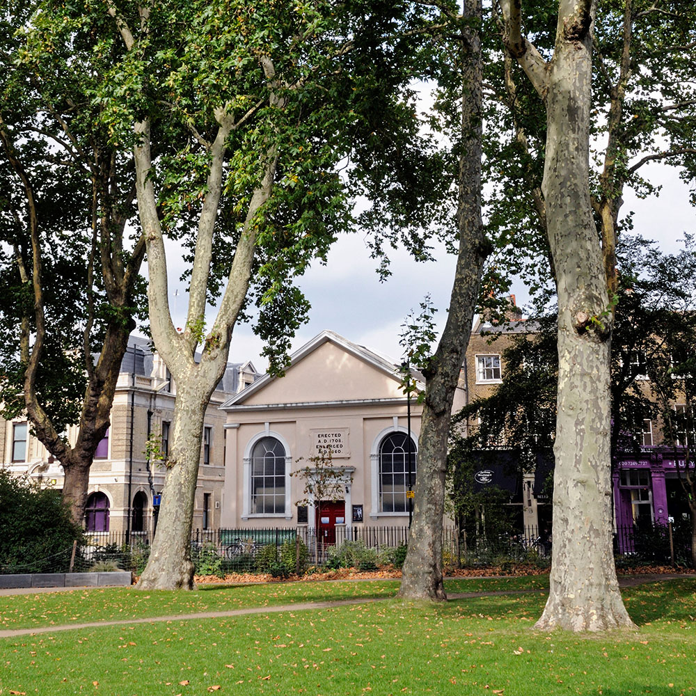 A low chapel building sits on the edge of a London park, with townhouses on each side.
