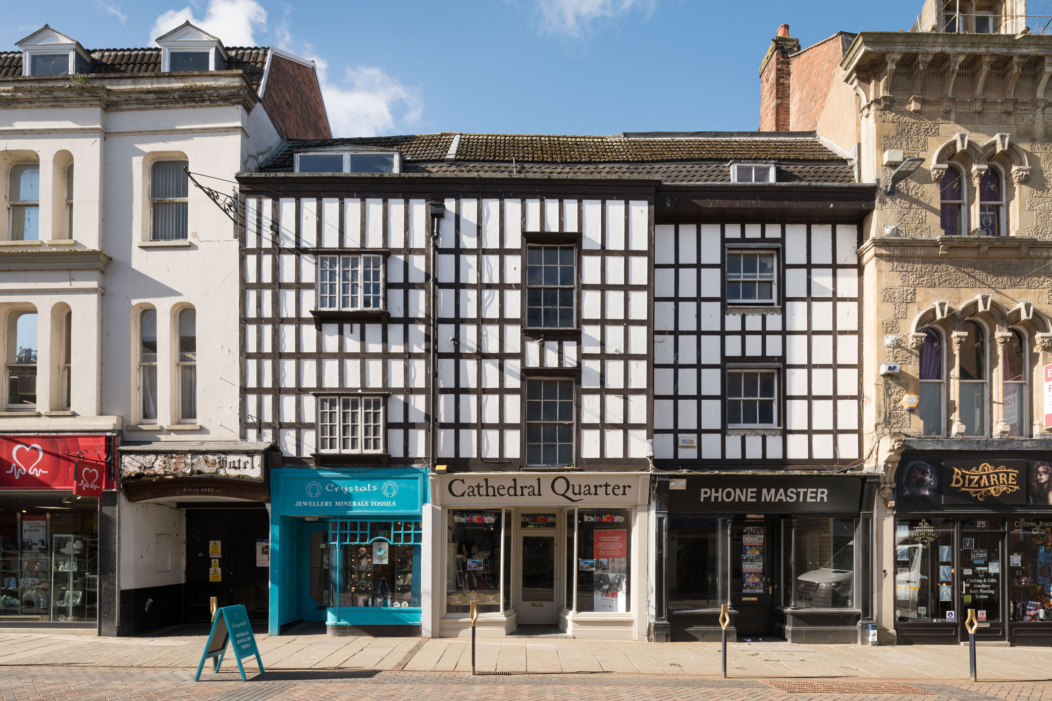 A three storey timber-framed building with shop fronts and a carriage entrance to the ground floor.