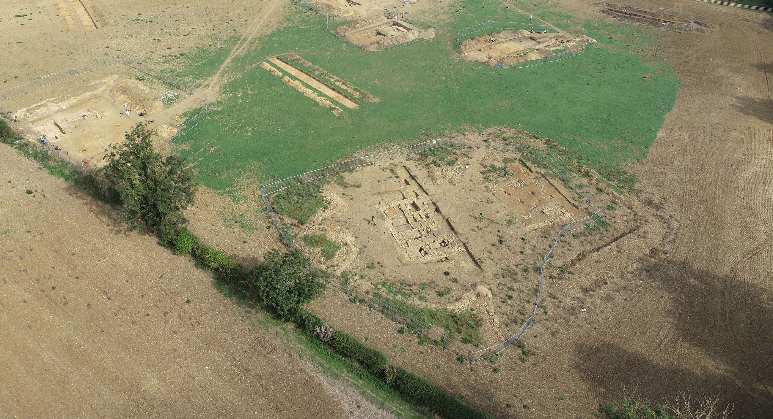 Aerial view of an excavation with trenches containing foundations of stone walls.