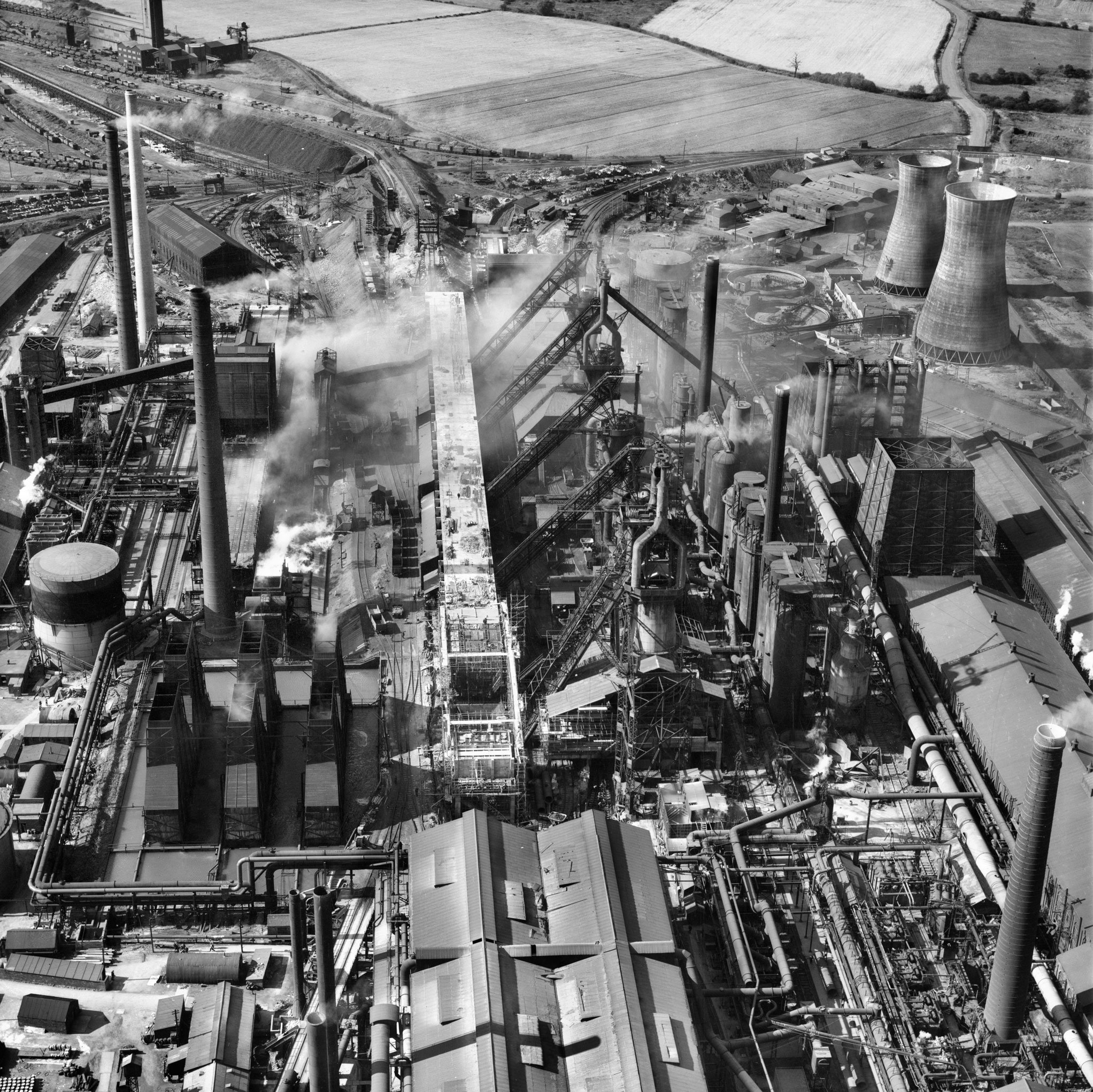 A black and white aerial photograph showing an industrial complex with workshops, chimneys and cooling towers.