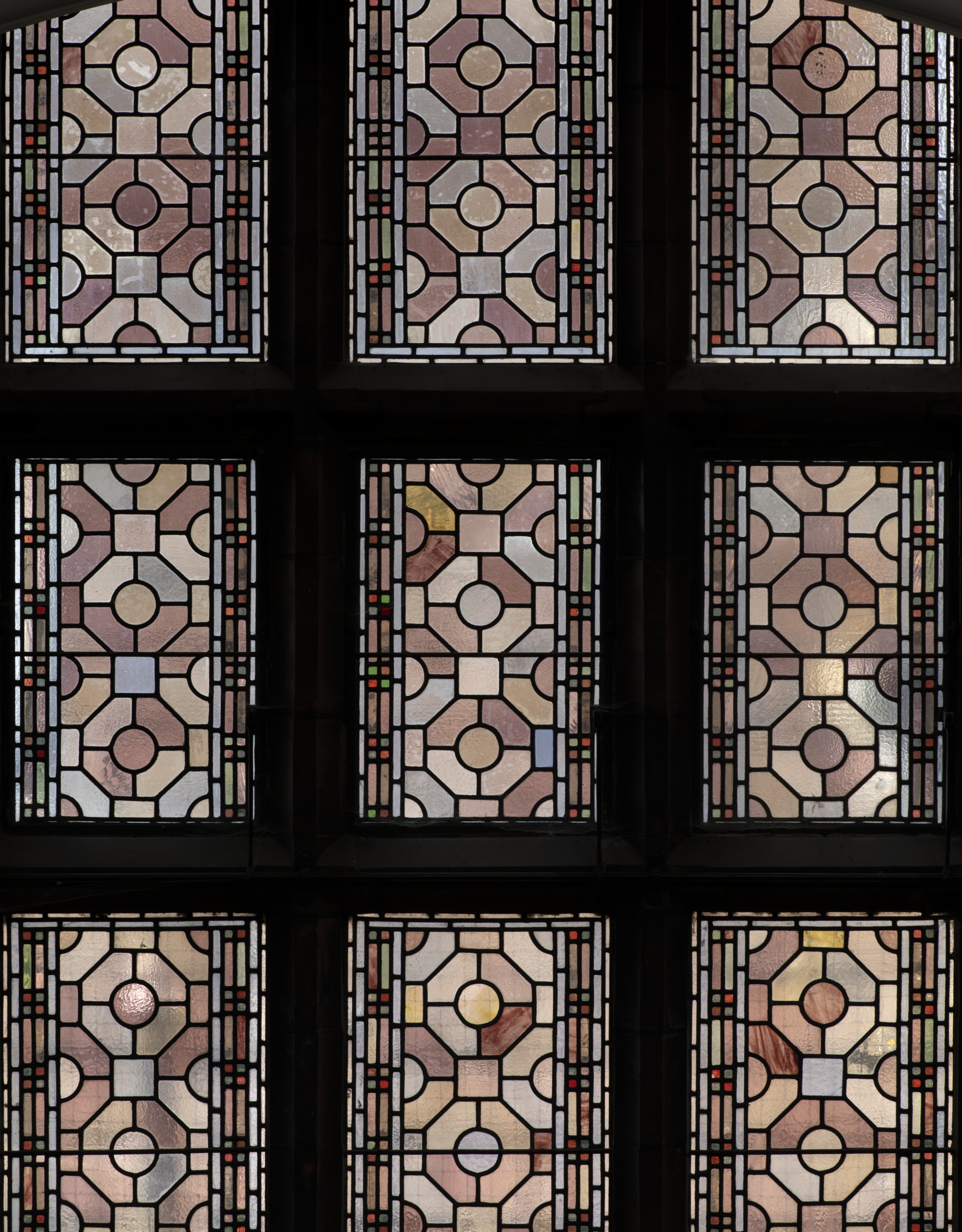 the photograph shows geometric stained glass in muted colours.