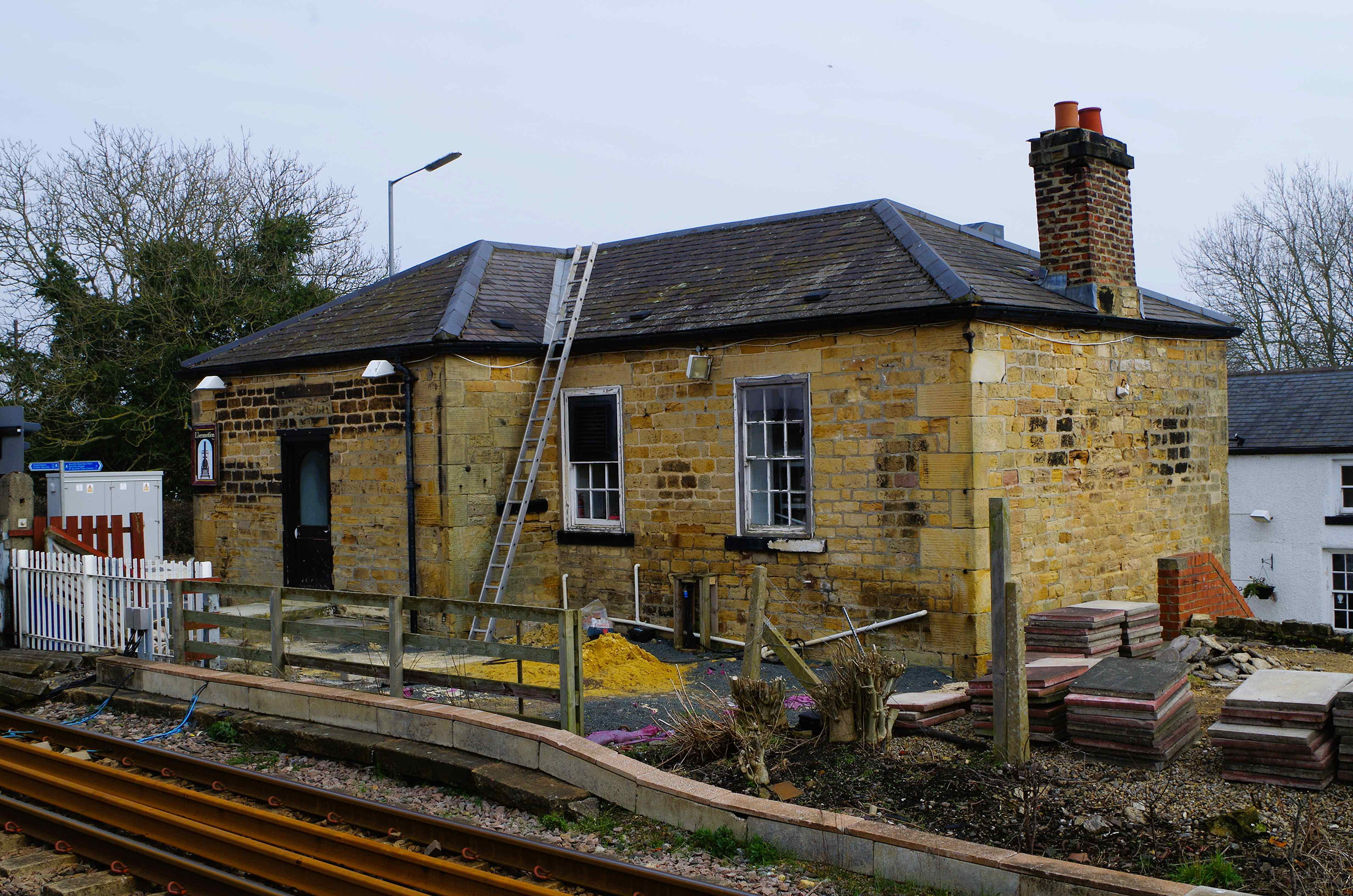 A stone building next to a railway track. 