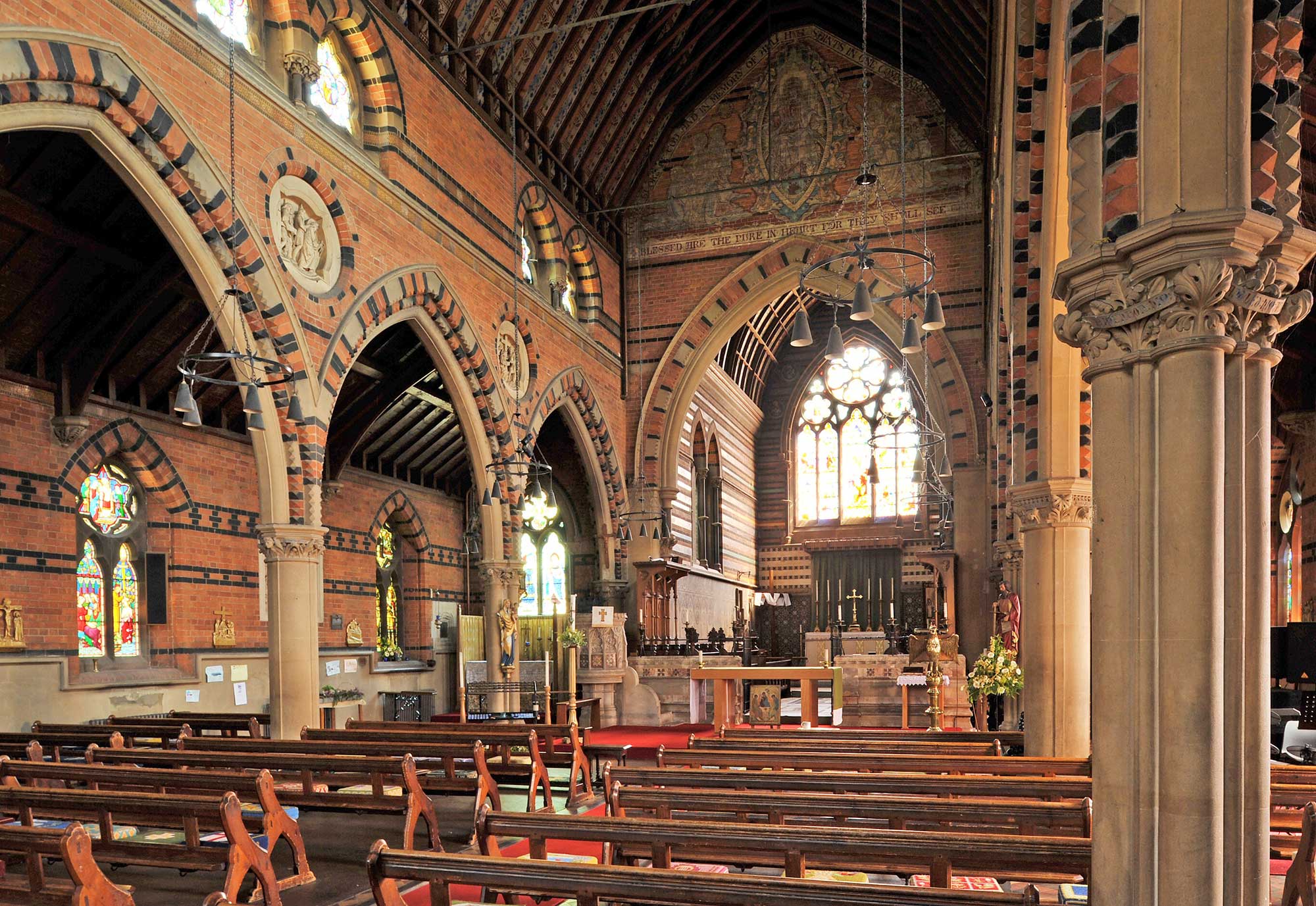 The interior of a church where the arches are composed of patterns of white stone and red and black bricks and the walls with red and black bricks.