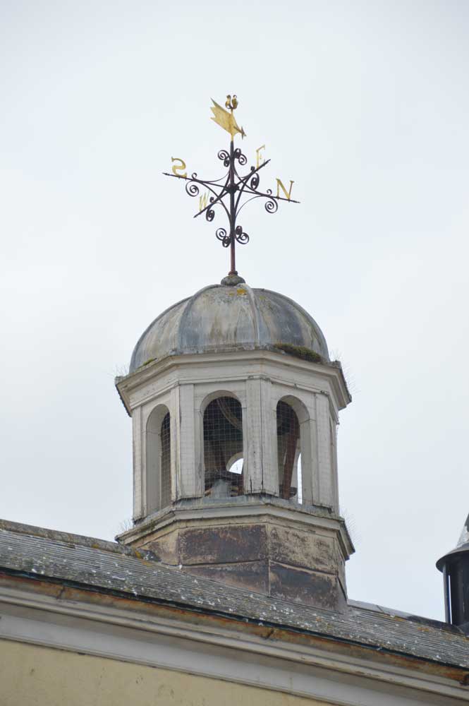 A photograph of a small octagonal bell tower on the rooftop of the Guildhall. It has round-headed openings and a domed lead roof, with an ornate weathervane on top.