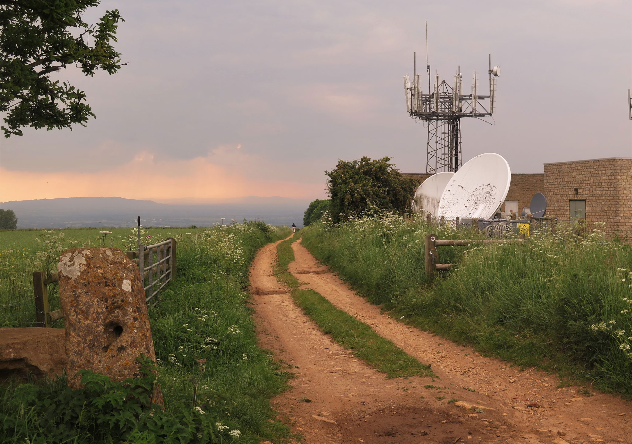 A photograph of hill landscape, with a cluster of modern communications structures to the right of the picture