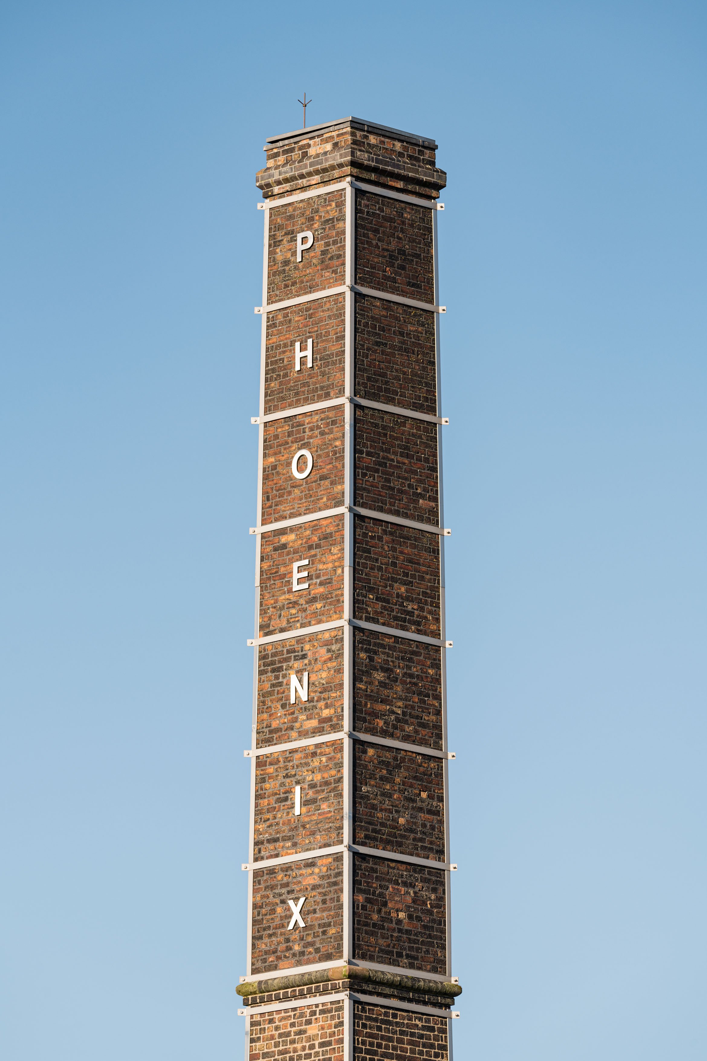 A tall brick chimney against a blue sky 